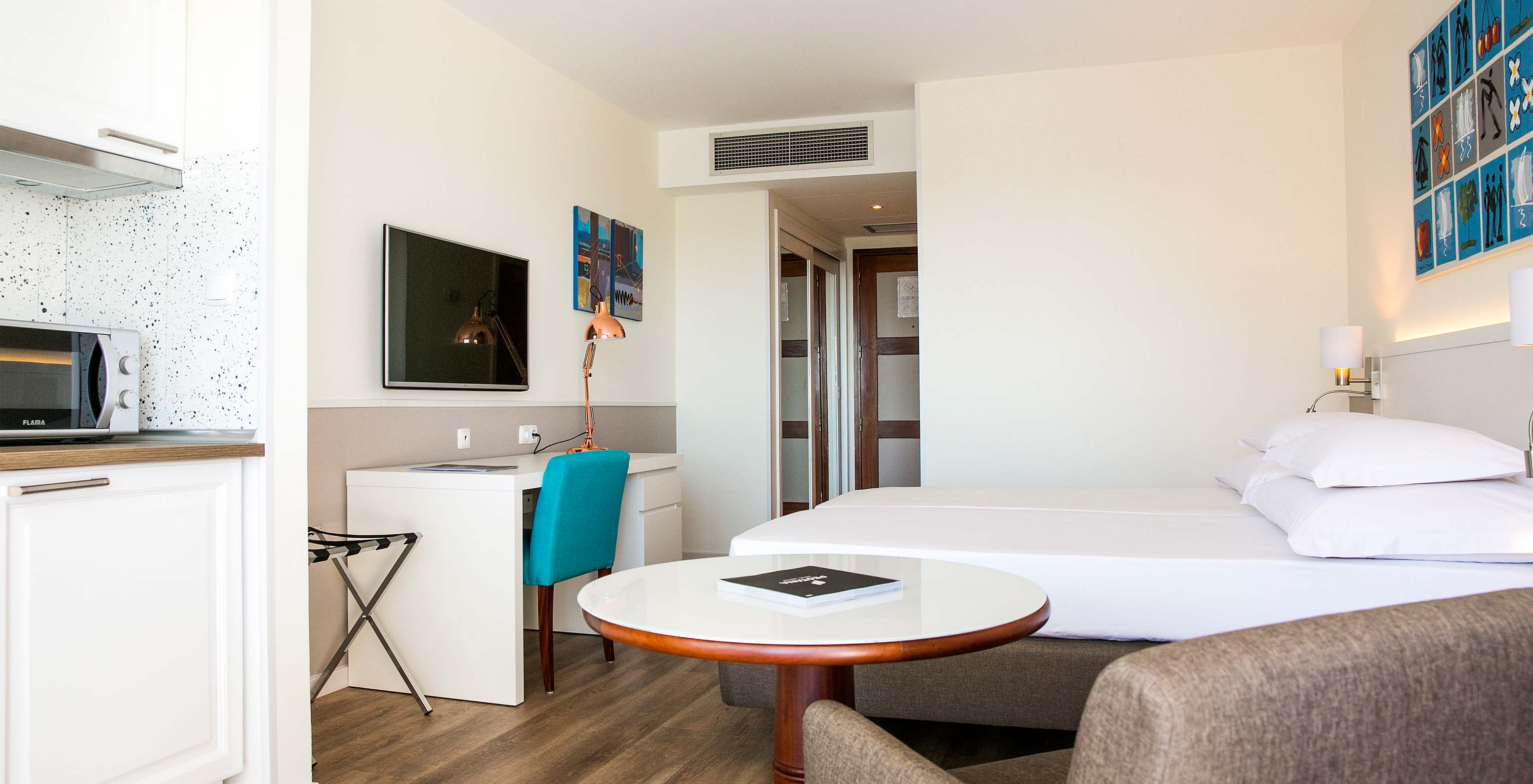 The Deluxe Sea View room at Pestana Cascais has two single beds, a TV, a desk, and a kitchenette