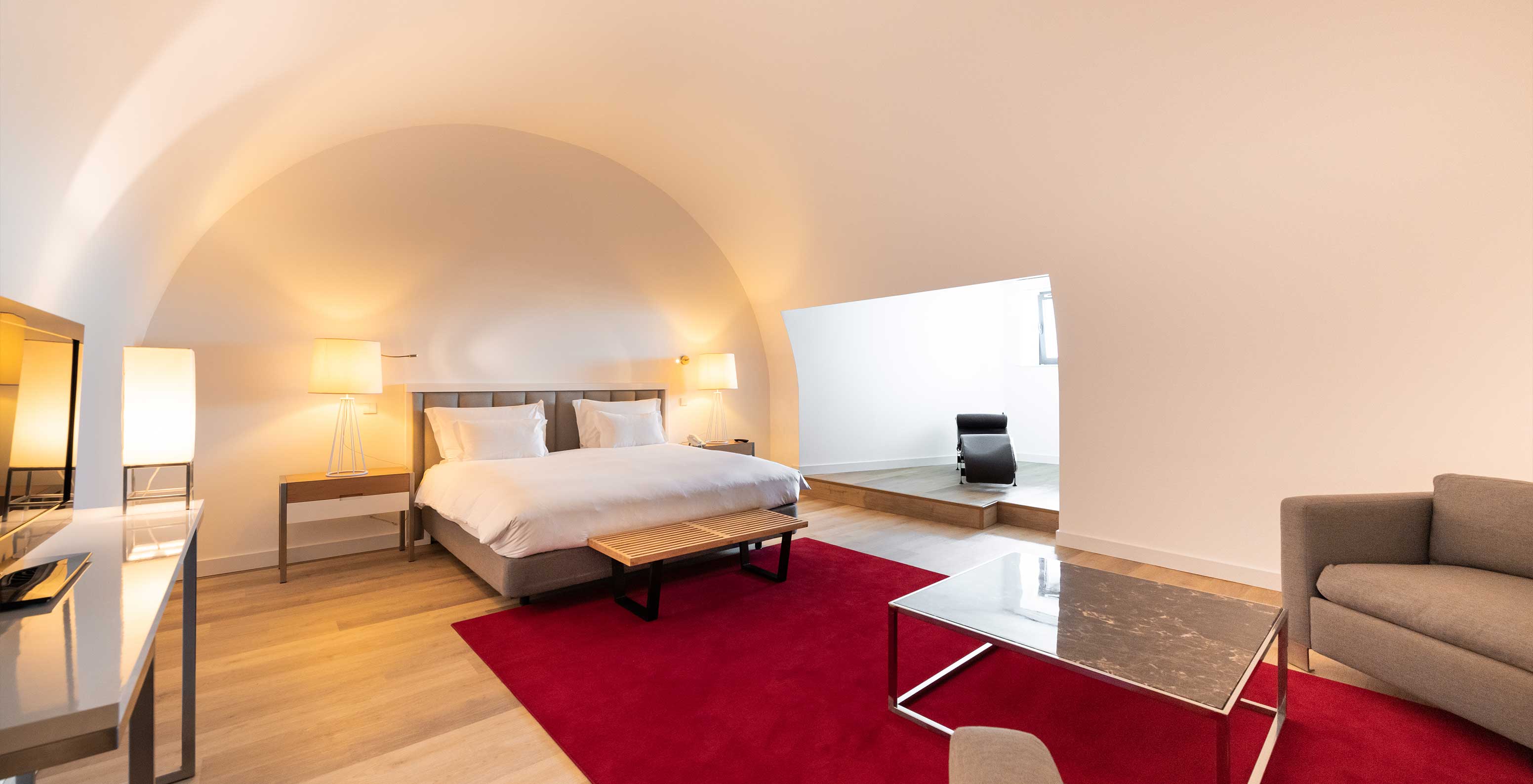 The Junior Family Suite at Pestana Cidadela Cascais is spacious with a high ceiling, a double bed, and a desk