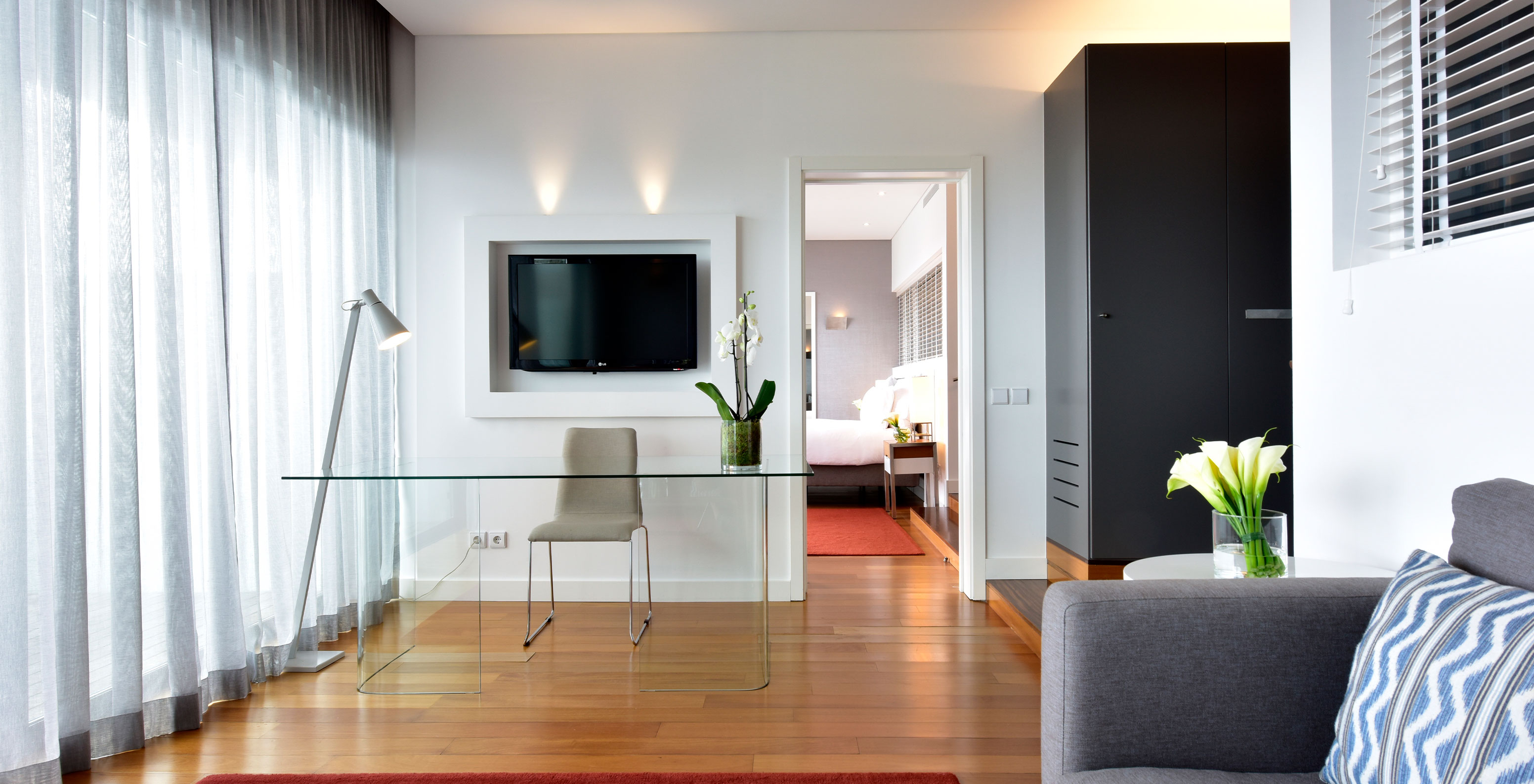 The Suite at Pestana Cidadela Cascais has a living room with a gray sofa, TV, desk, and table