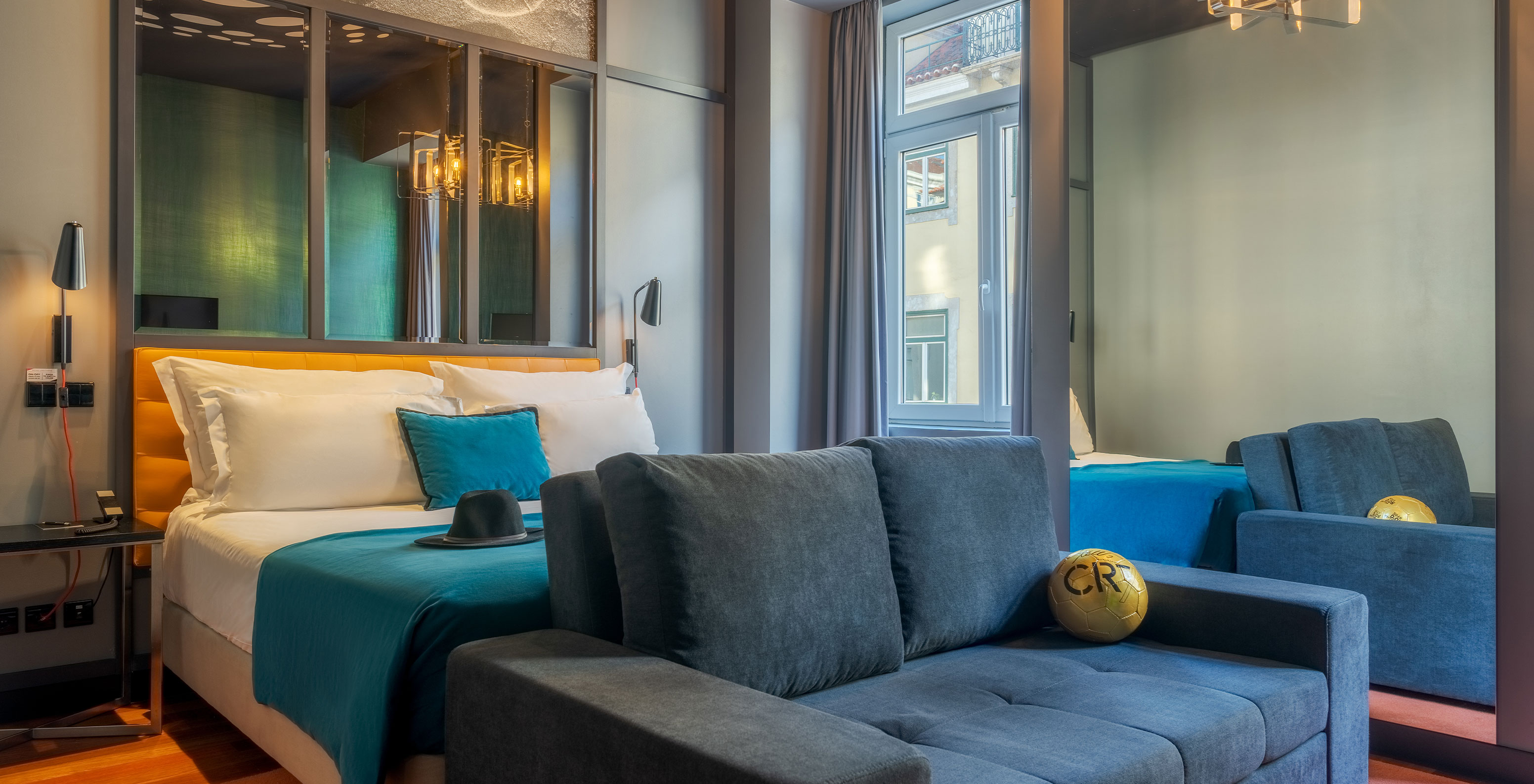 The CR7 Family Hat-Trick Room at Pestana CR7 Lisboa includes a sofa, a bed, and a mirror above the bed