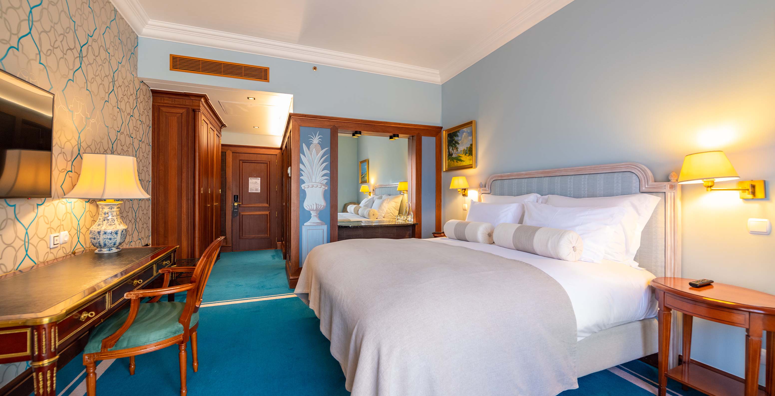 The Premium Balcony room at Pestana Palace Lisbon has a double bed, wooden paneling with a mirror, and cabinets