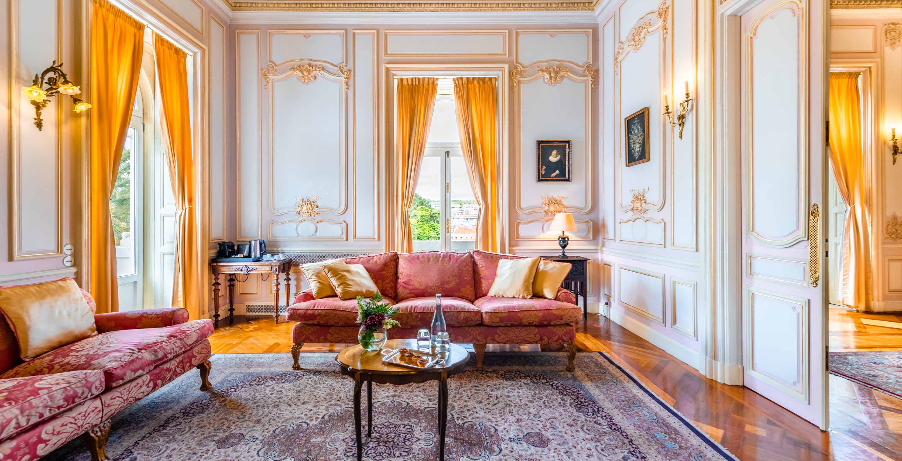 The Suite D. Carlos do Pestana Palace Lisboa has a large luxurious living room with two sofas, a rug and two windows