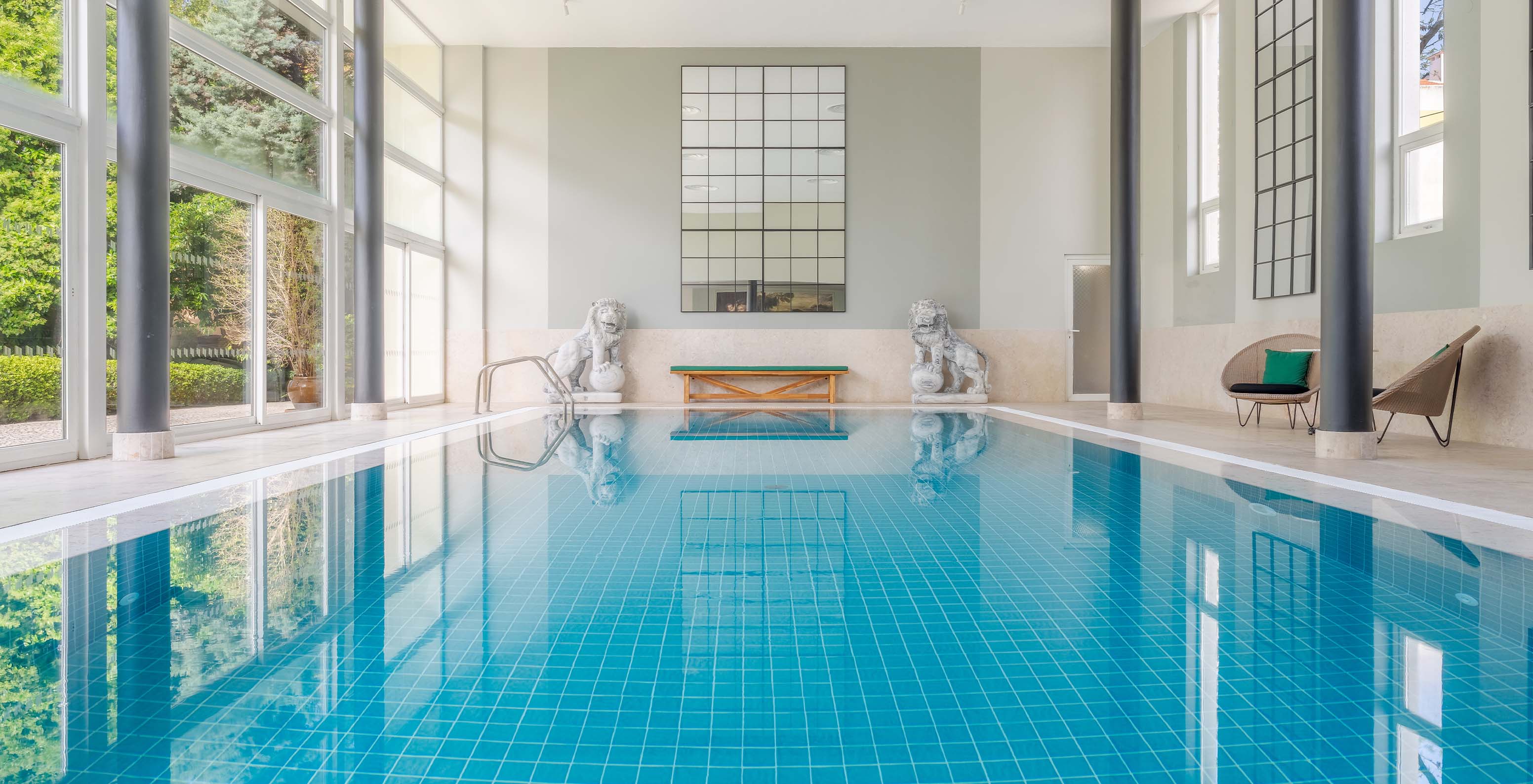 Indoor pool at Palace Lisboa, a hotel in a palace in Lisbon, with natural light and two lion sculptures