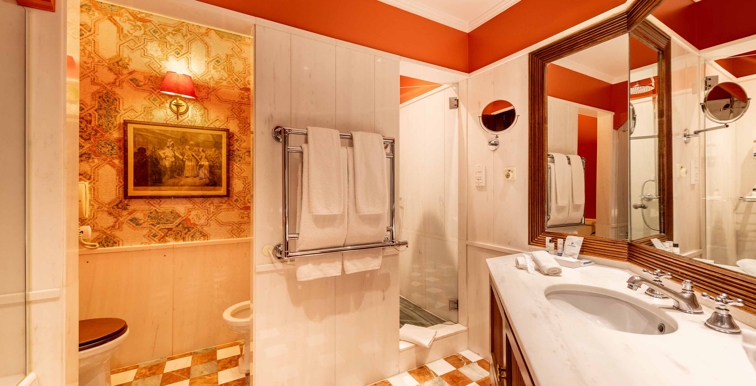 The Suite Collection at Pestana Palace Lisbon features a white marble bathroom with a bathtub, shower, toilet, and towels