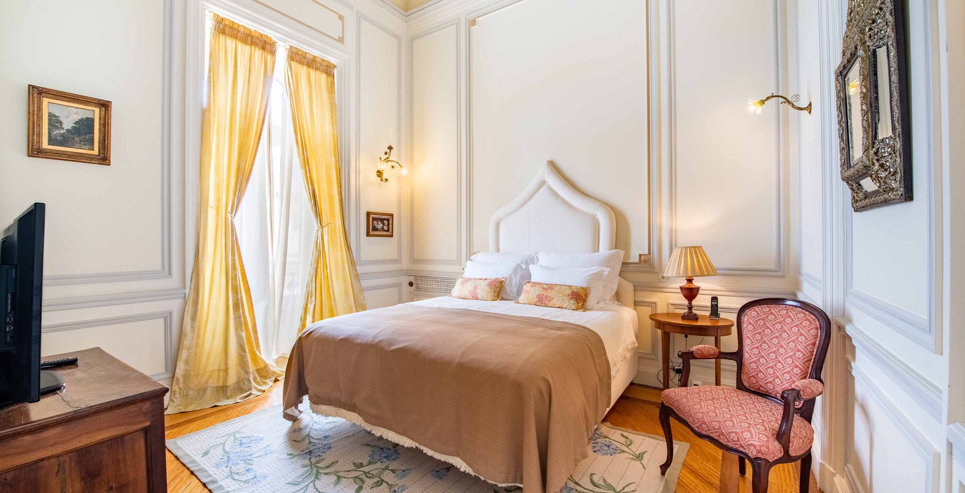 The Suite D. Amélia at Pestana Palace Lisbon has a double bed, a wooden bedside table, a chair, a rug, and a window