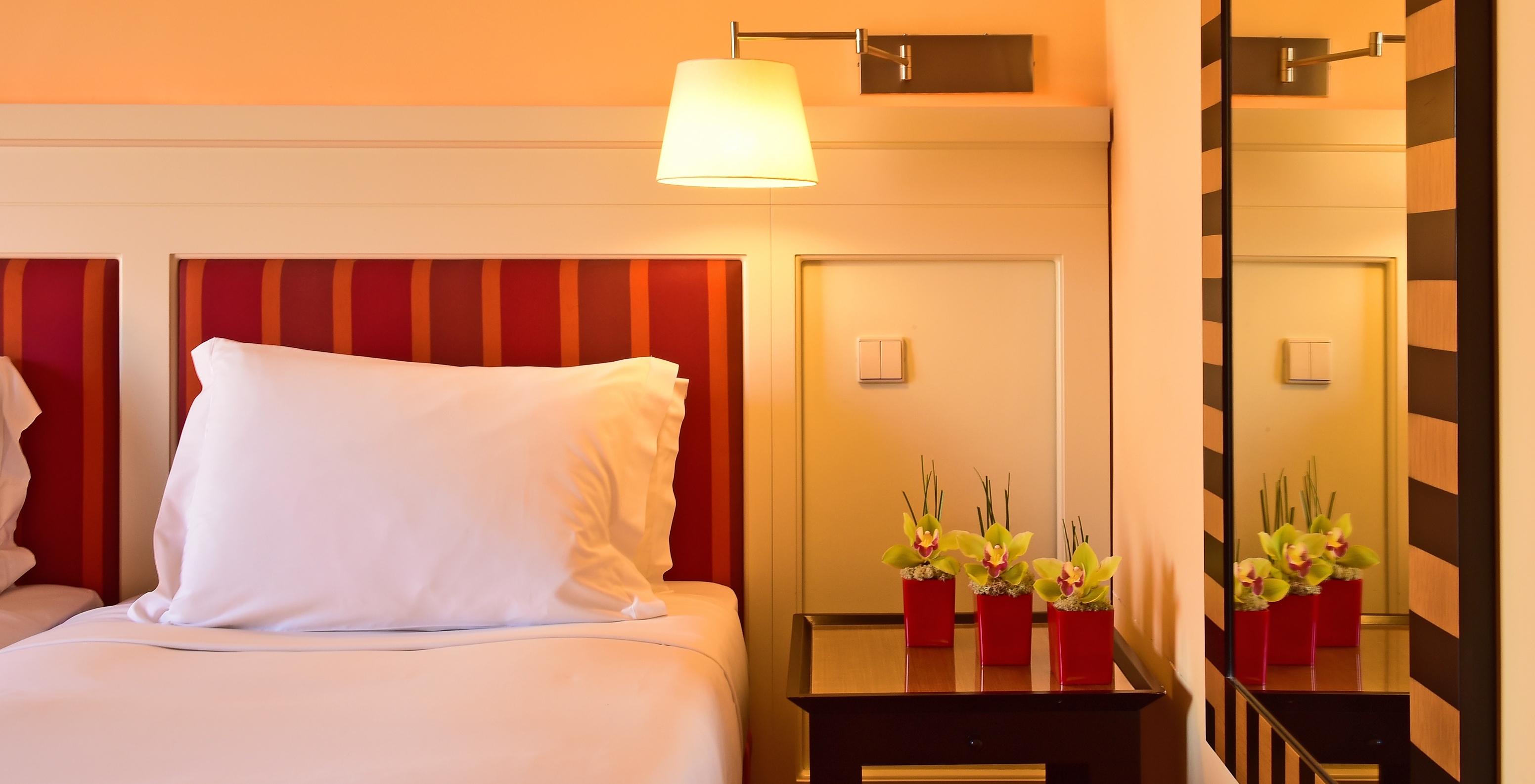 The Classic Double of Pestana Sintra Golf has a bed, a mirror, a lamp, and a bedside table with flowers