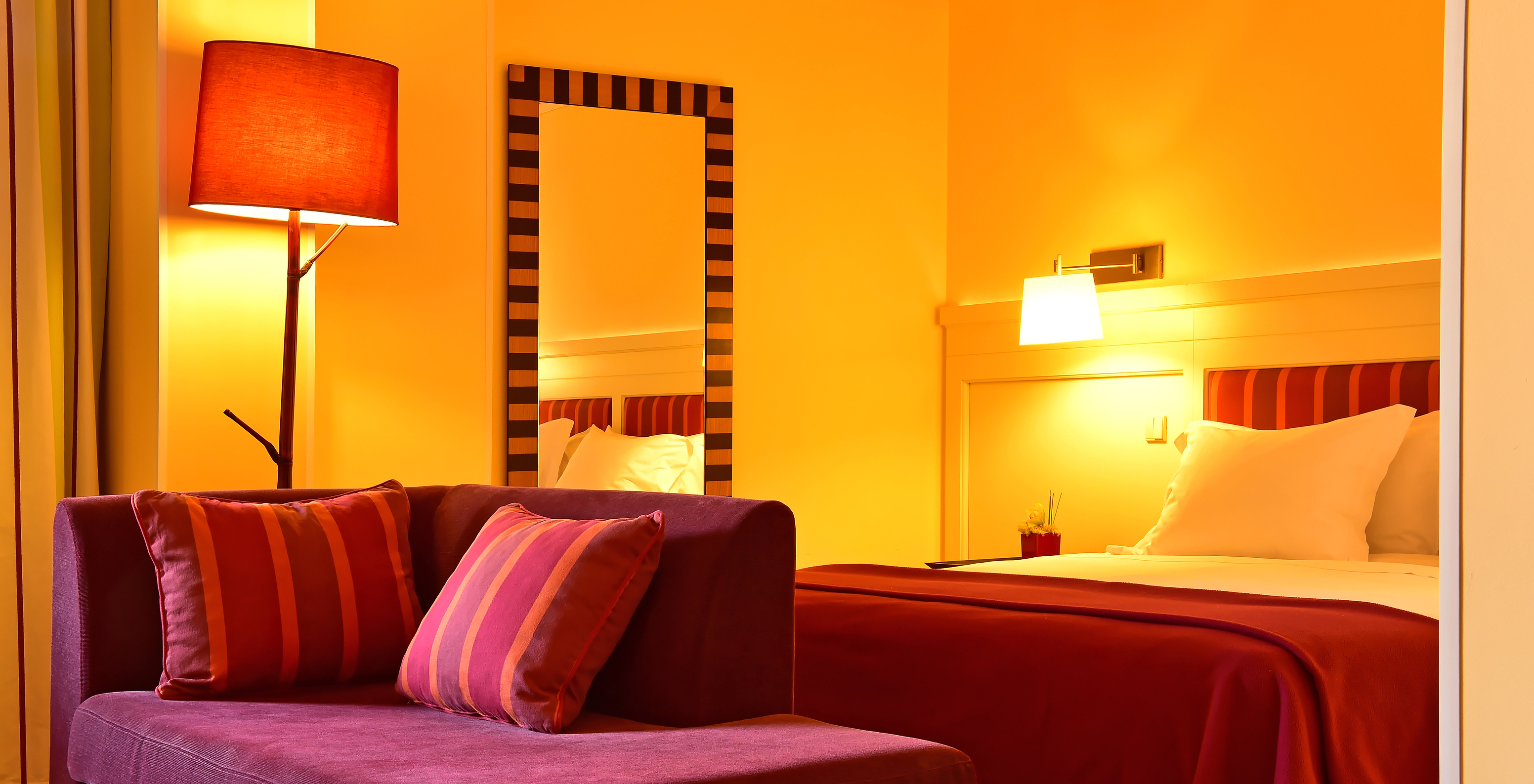 The Junior Suite of Pestana Sintra Golf has a double bed, a mirror on the wall, and a small red sofa