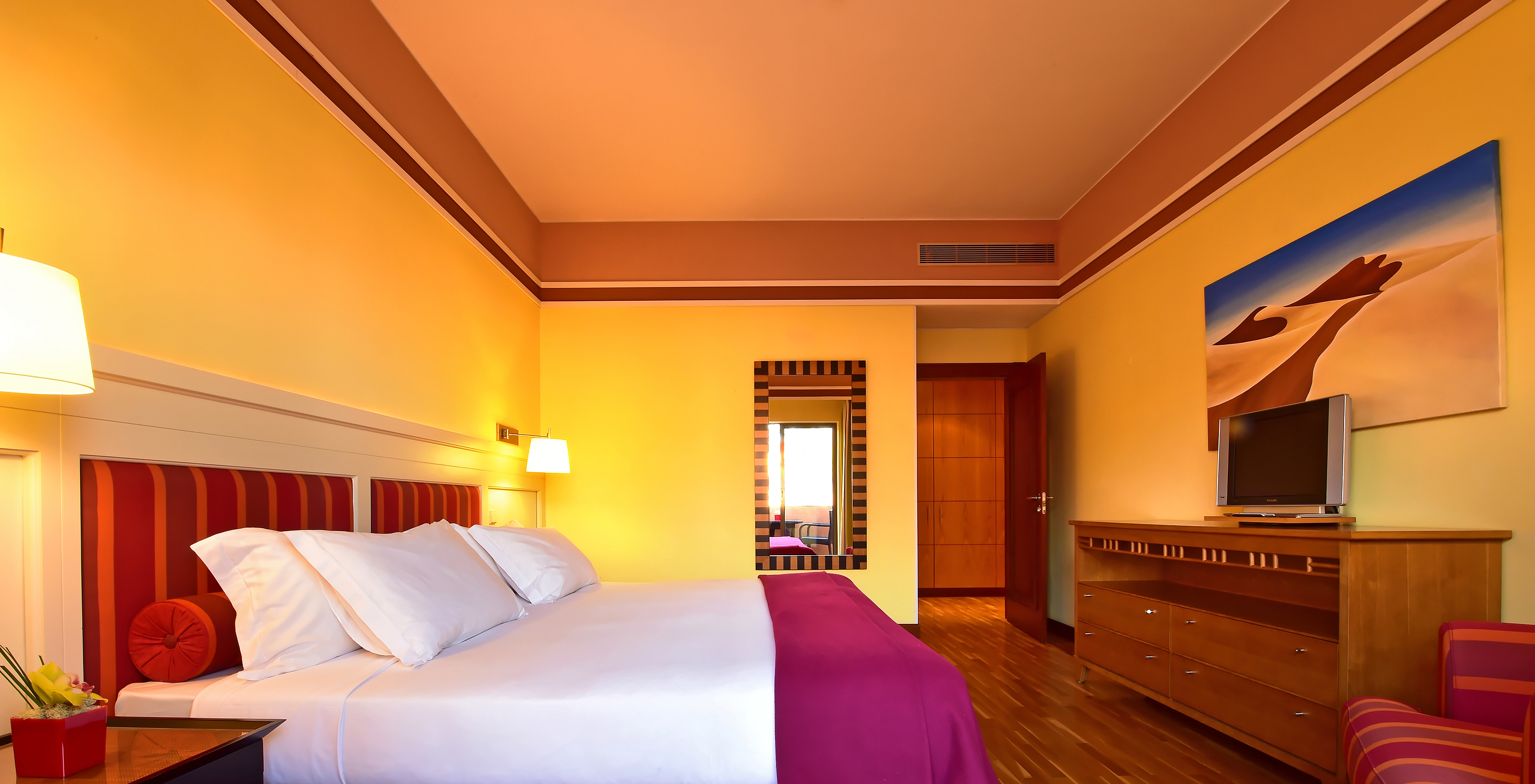 The Superior Suite of Pestana Sintra Golf has a double bed, a mirror on the wall, and a unit with a small television