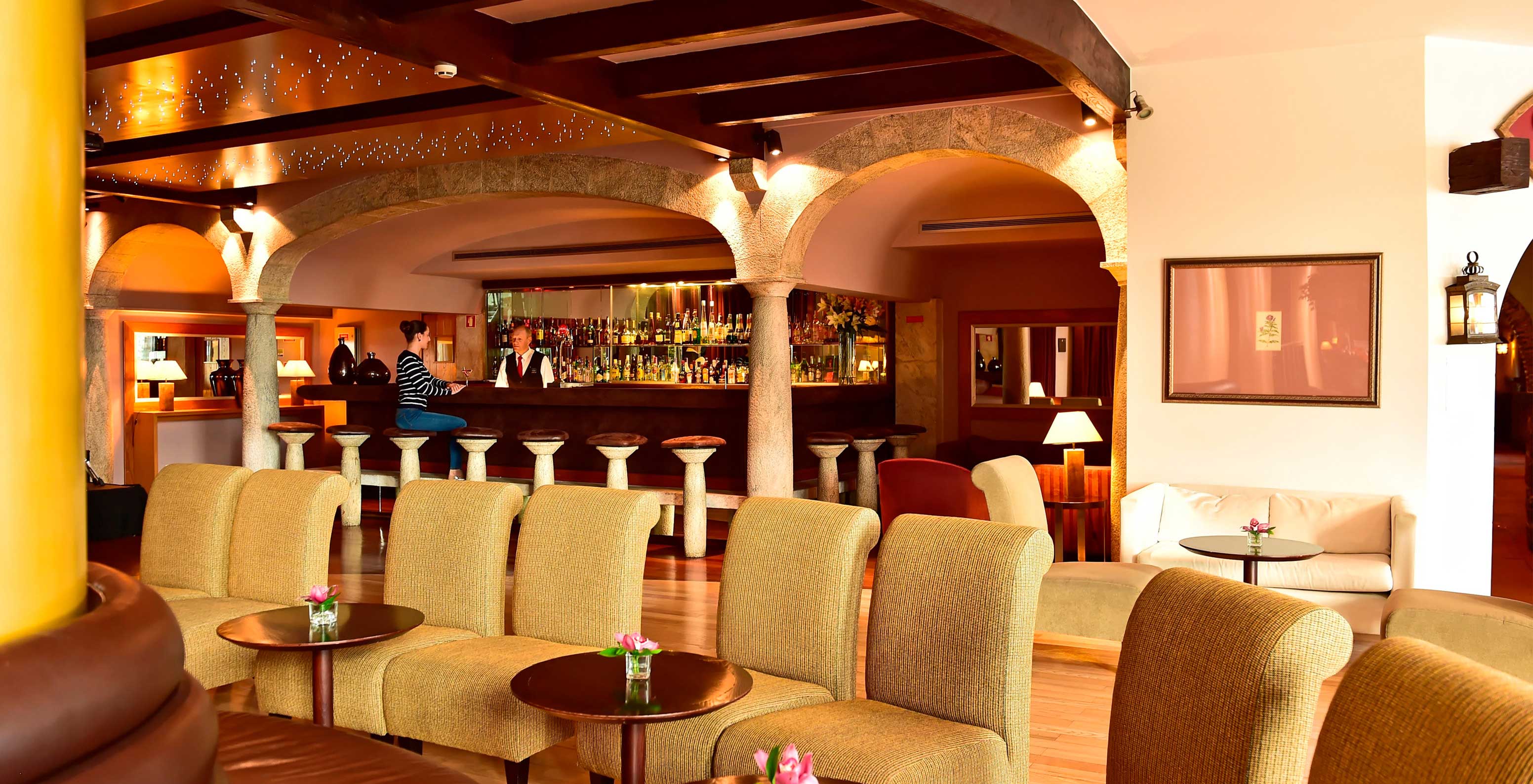 Pestana Carlton Madeira, a hotel in the center of Funchal by the sea, has a bar with various drinks and chairs