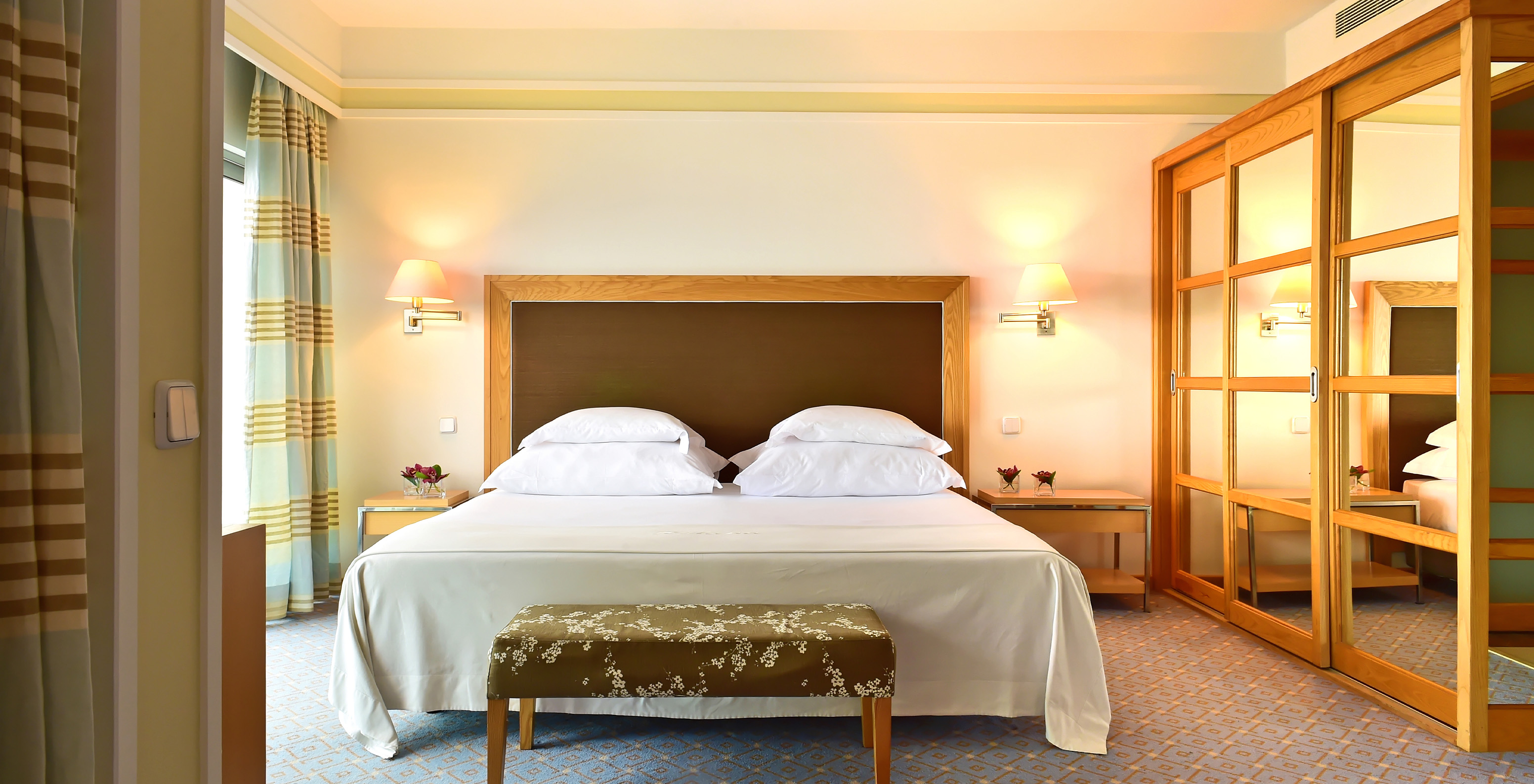 The Junior Suite at Pestana Carlton Madeira has a double bed with a bench at the foot and a wardrobe with mirrors