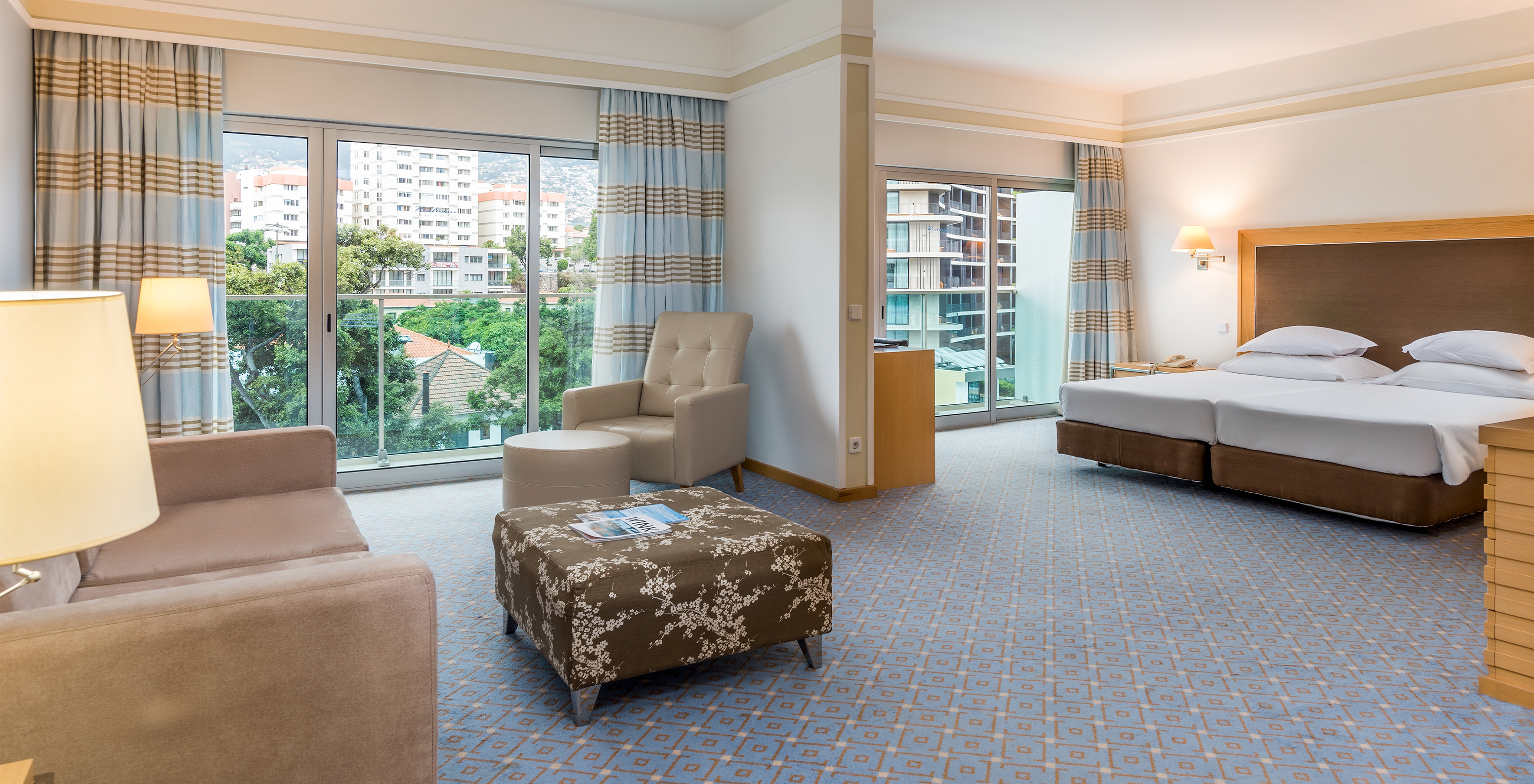 The Family Double Room at Pestana Carlton Madeira has a seating area with sofas, a double bed, and two balconies