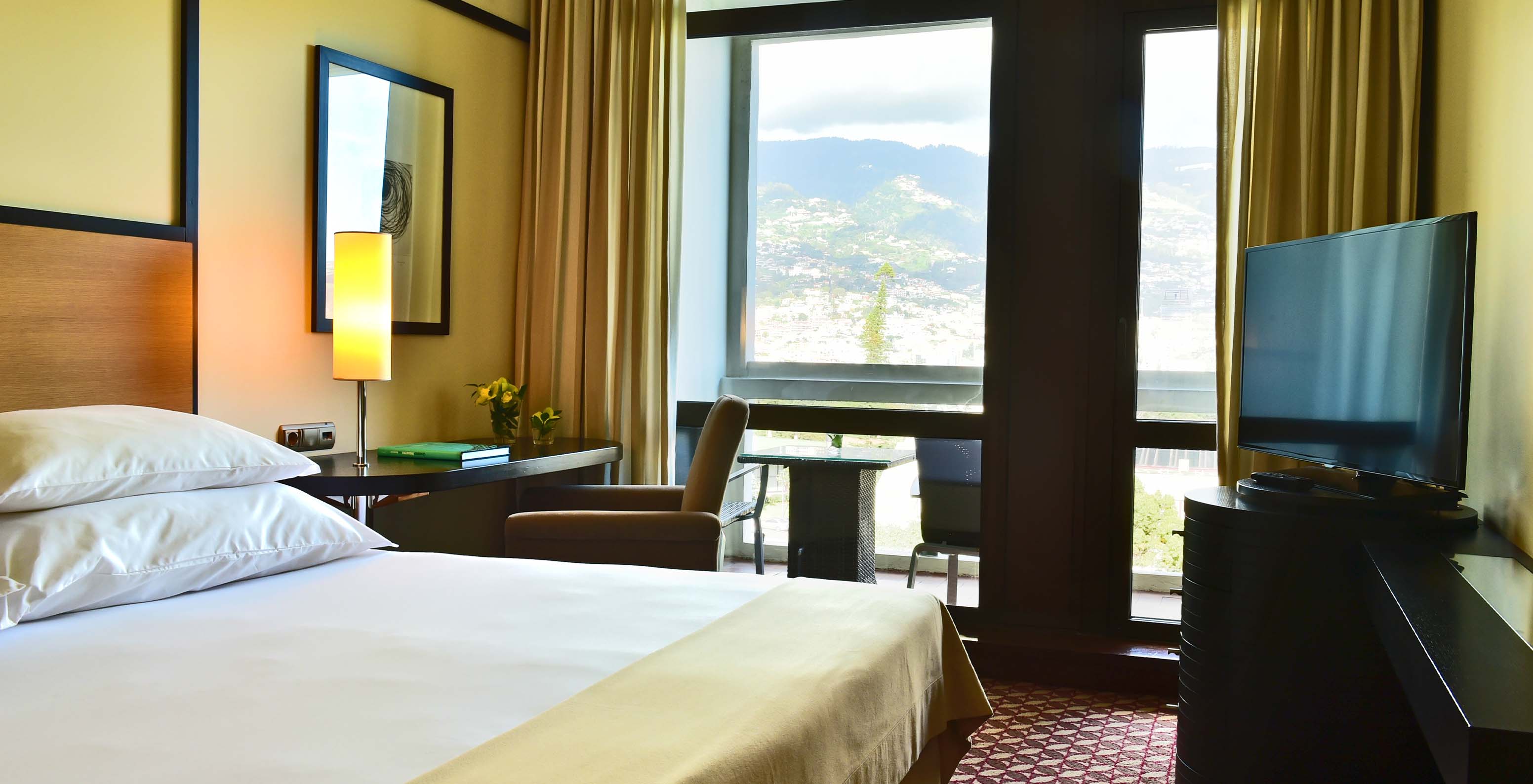 The Classic Garden View room at Pestana Casino Park has a double bed, a TV, a desk, and a balcony