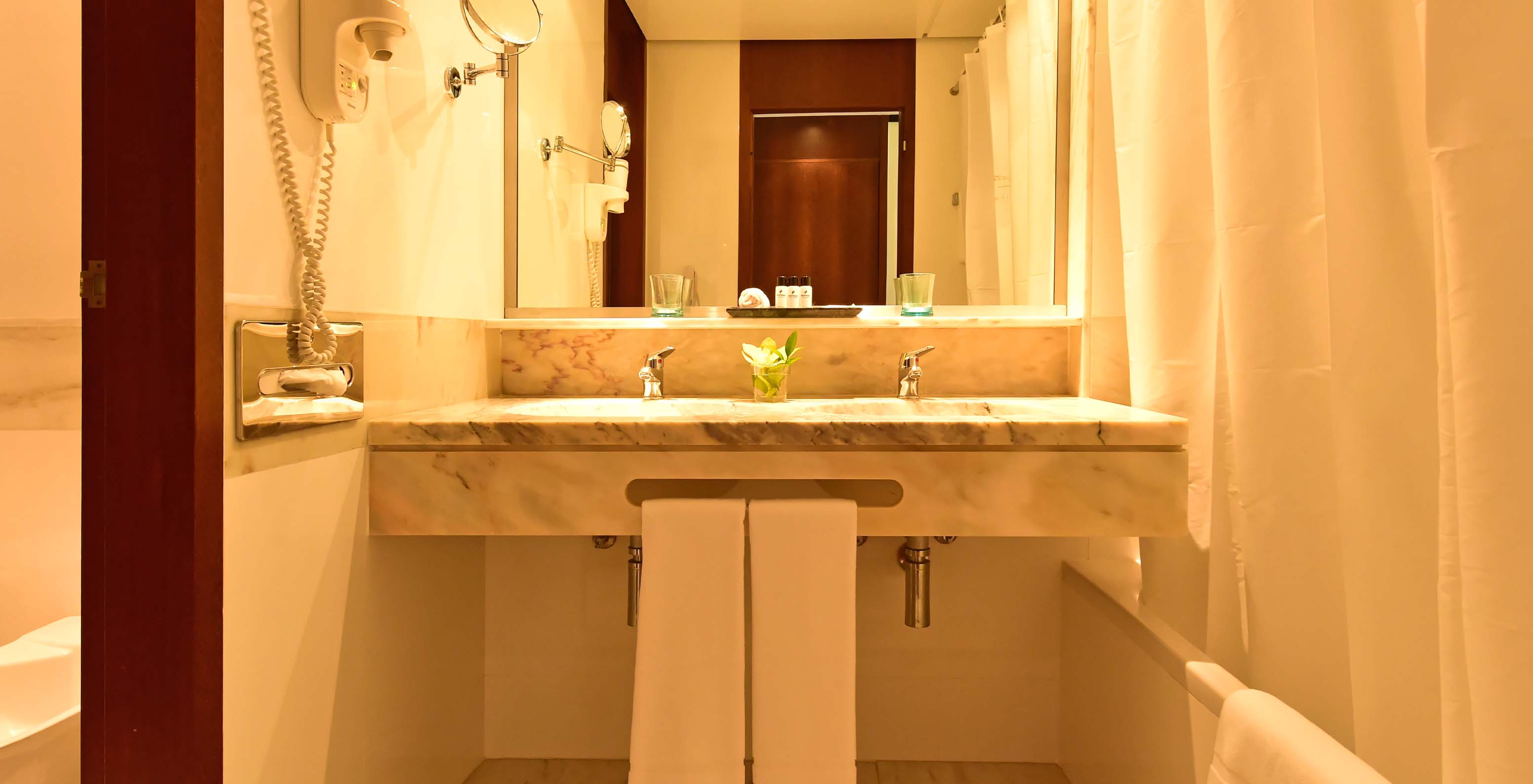 The Sea View Suite at Pestana Casino Park has a bathroom with a marble sink, bathtub, and hairdryer