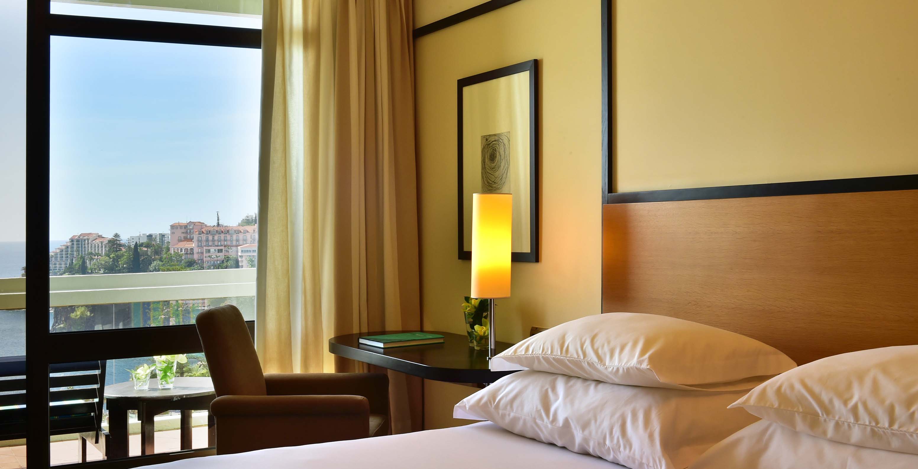 The Classic Side Sea View room at Pestana Casino Park has a double bed, a desk with a lamp, and a balcony