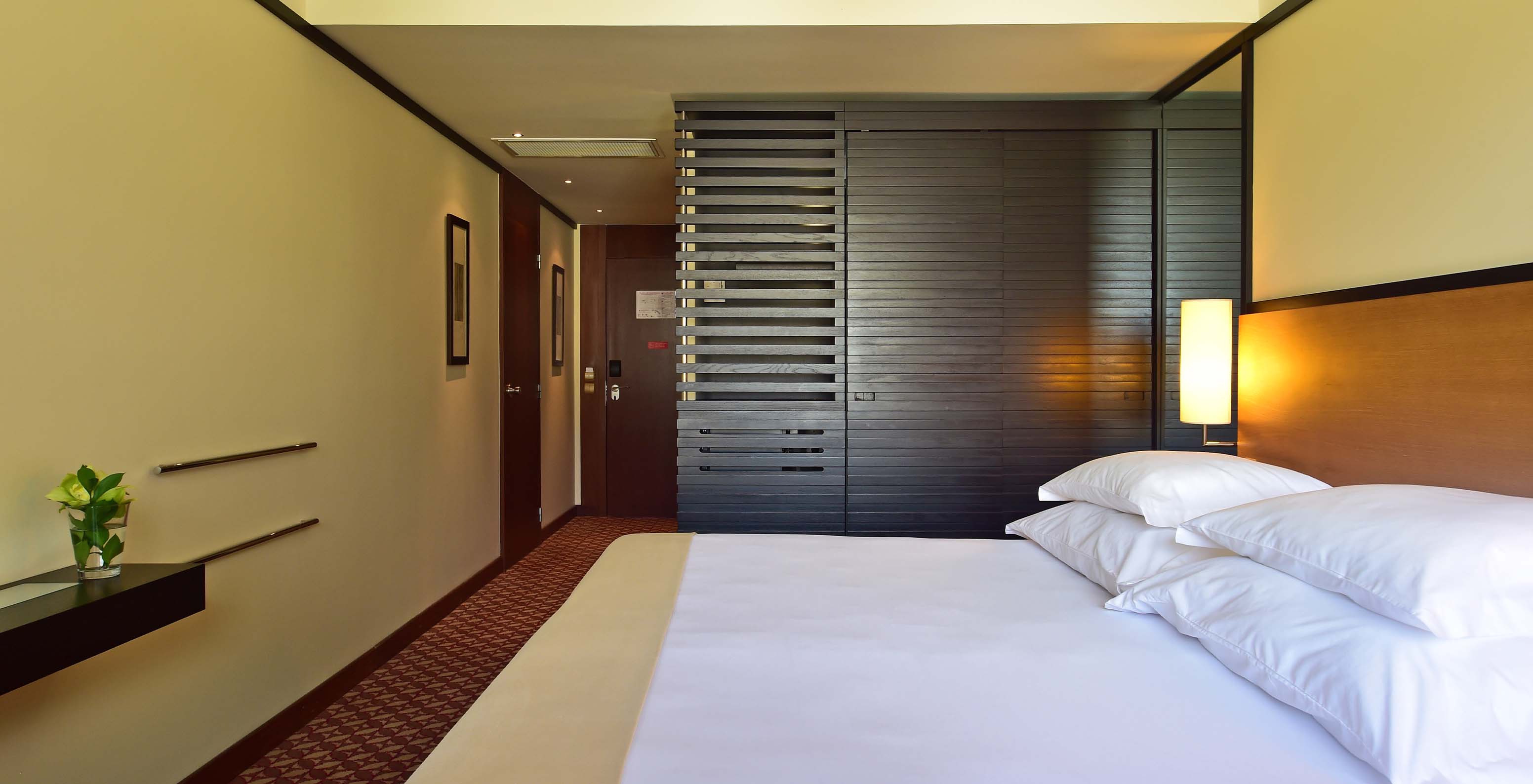 The Family Room at Pestana Casino Park has a double bed with a dark wood wardrobe and a lamp beside it