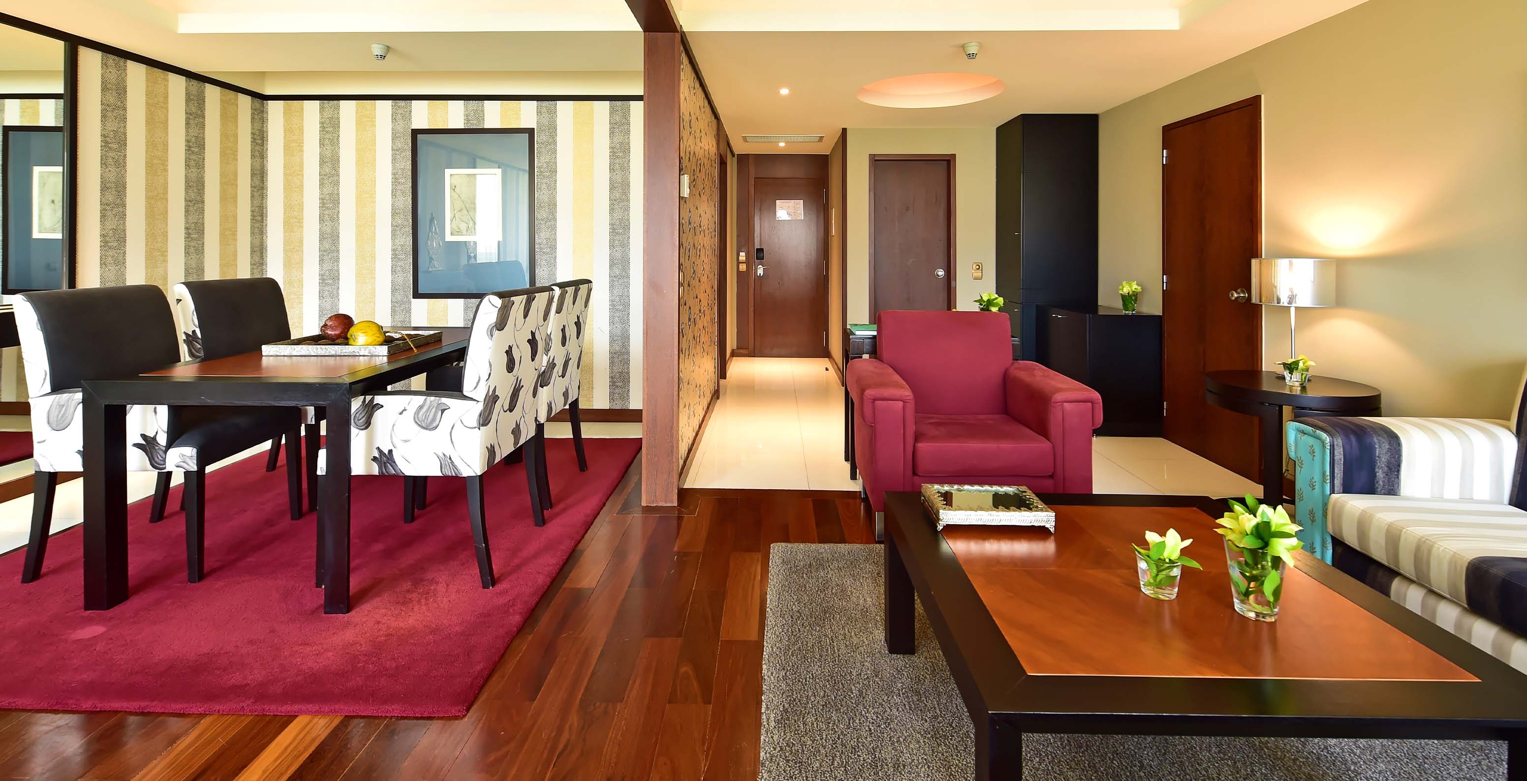 The Presidential Suite at Pestana Casino Park has a living room with a dining table, sofa, and armchair