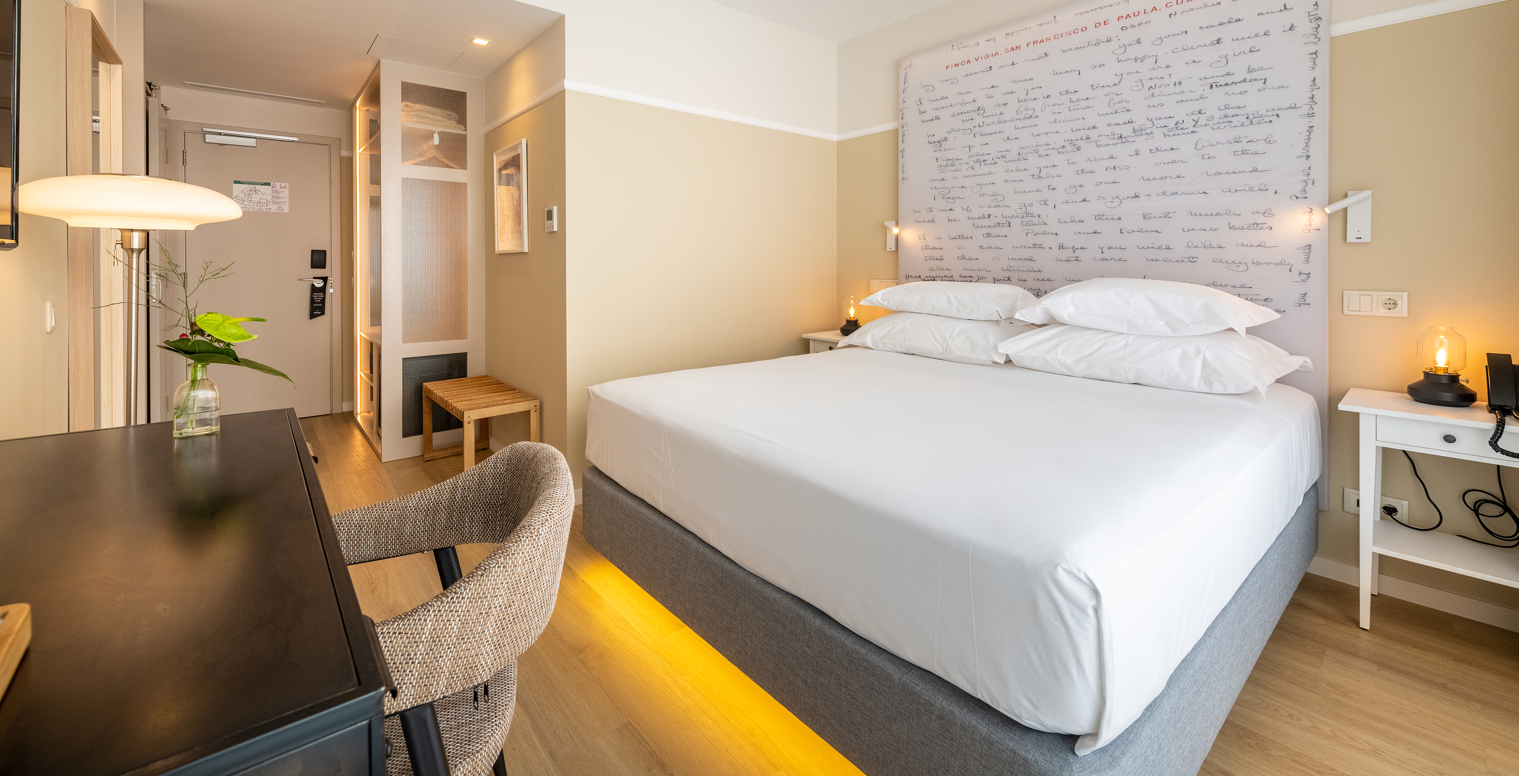 The Superior Room at Pestana Fisherman Village features a double bed with a headboard with written phrases and a desk