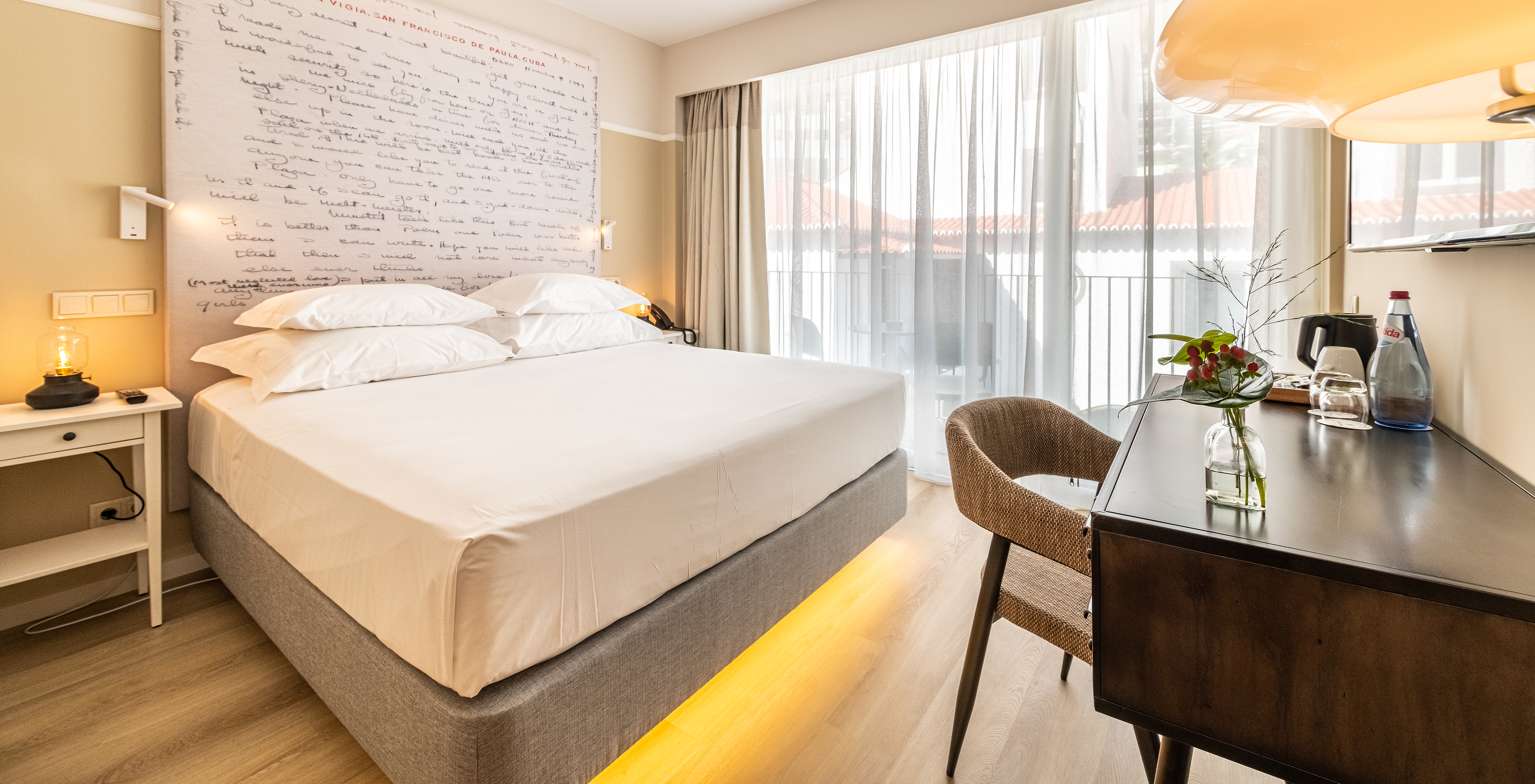 The Superior Room at Pestana Fisherman Village includes a double bed with a headboard with written phrases and a balcony