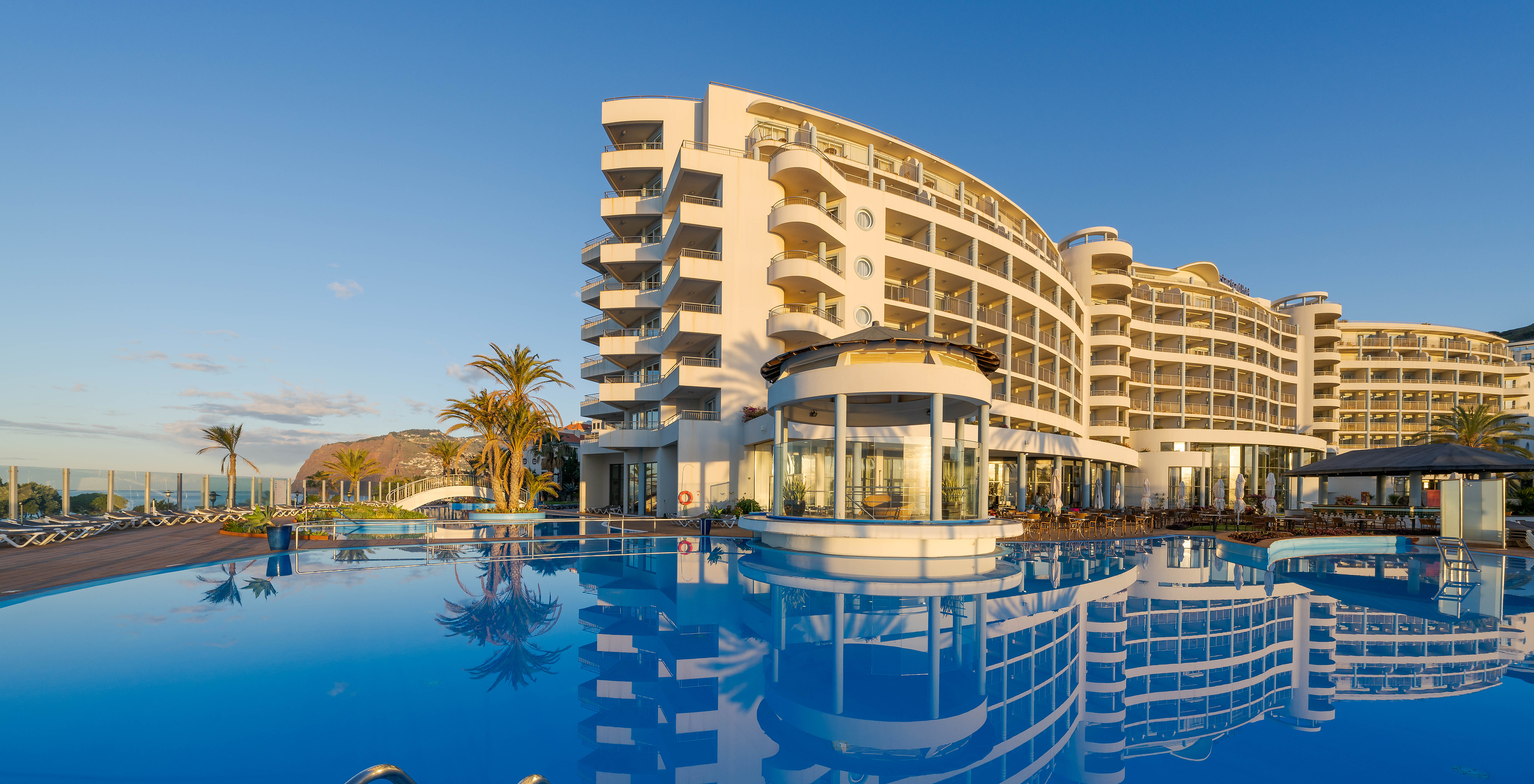 View over outdoor pool with light blue water, white hotel building in background