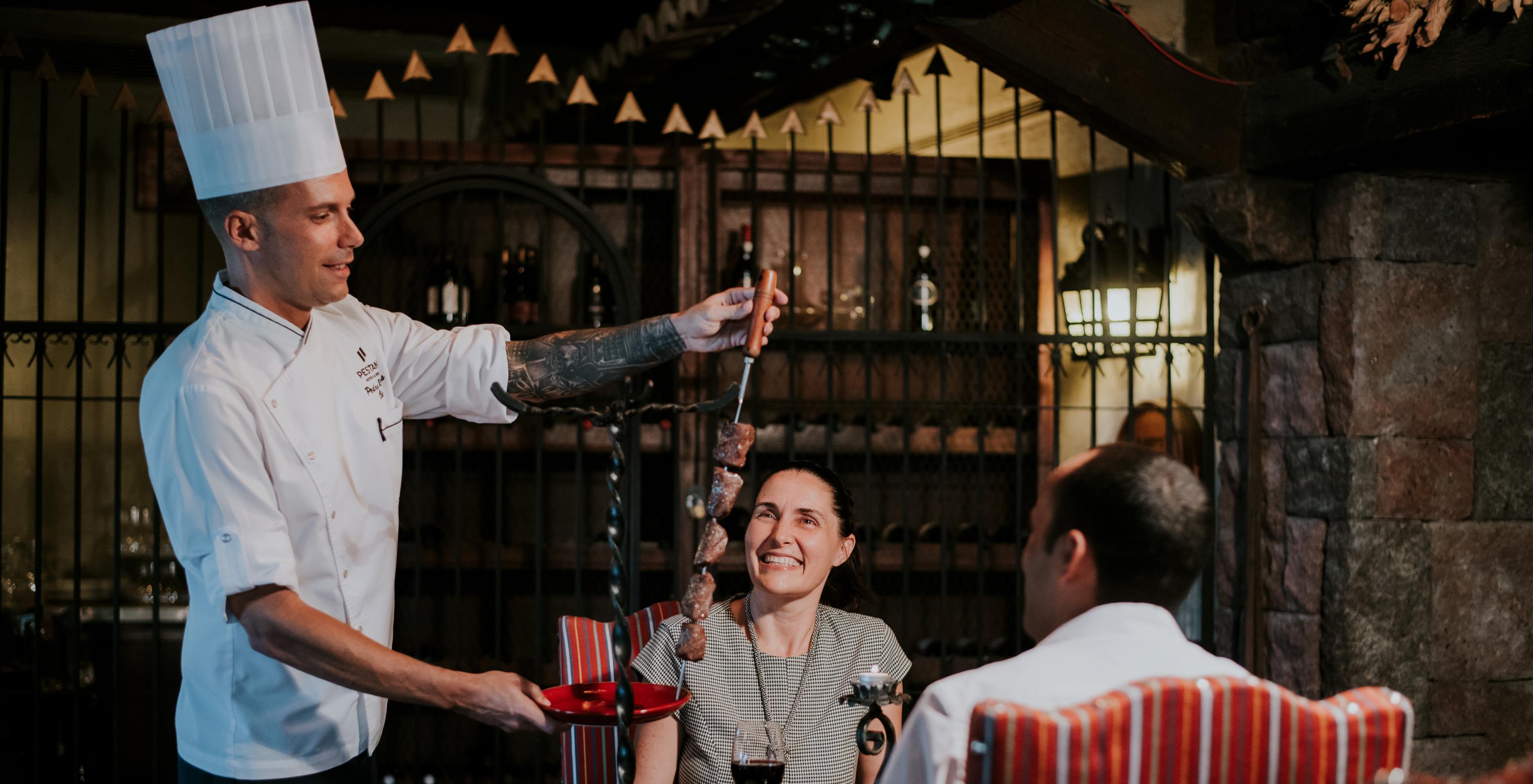 The Taverna Grill restaurant at the hotel in central Funchal, Madeira, has a chef serving meat skewers