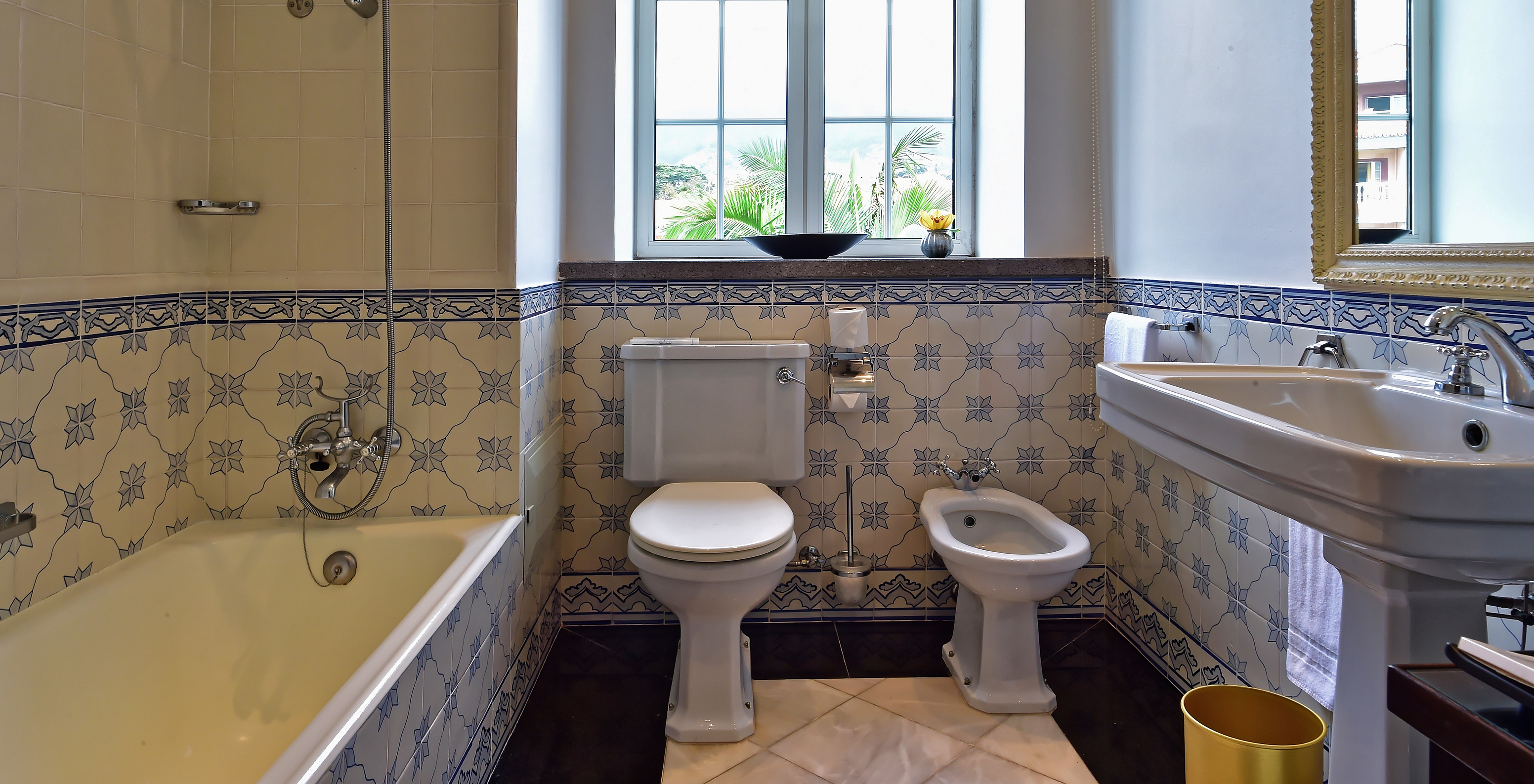 The Miramar Suite at Pestana Miramar has a bathroom with blue flower tiles, bathtub, toilet, bidet and sink