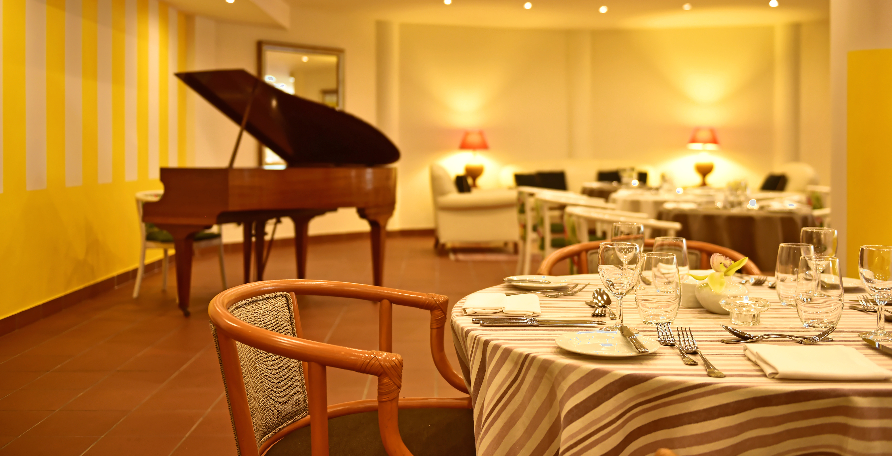 Restaurant of Pestana Ocean Bay, an all-inclusive hotel by the sea, with a set table and a piano in the background