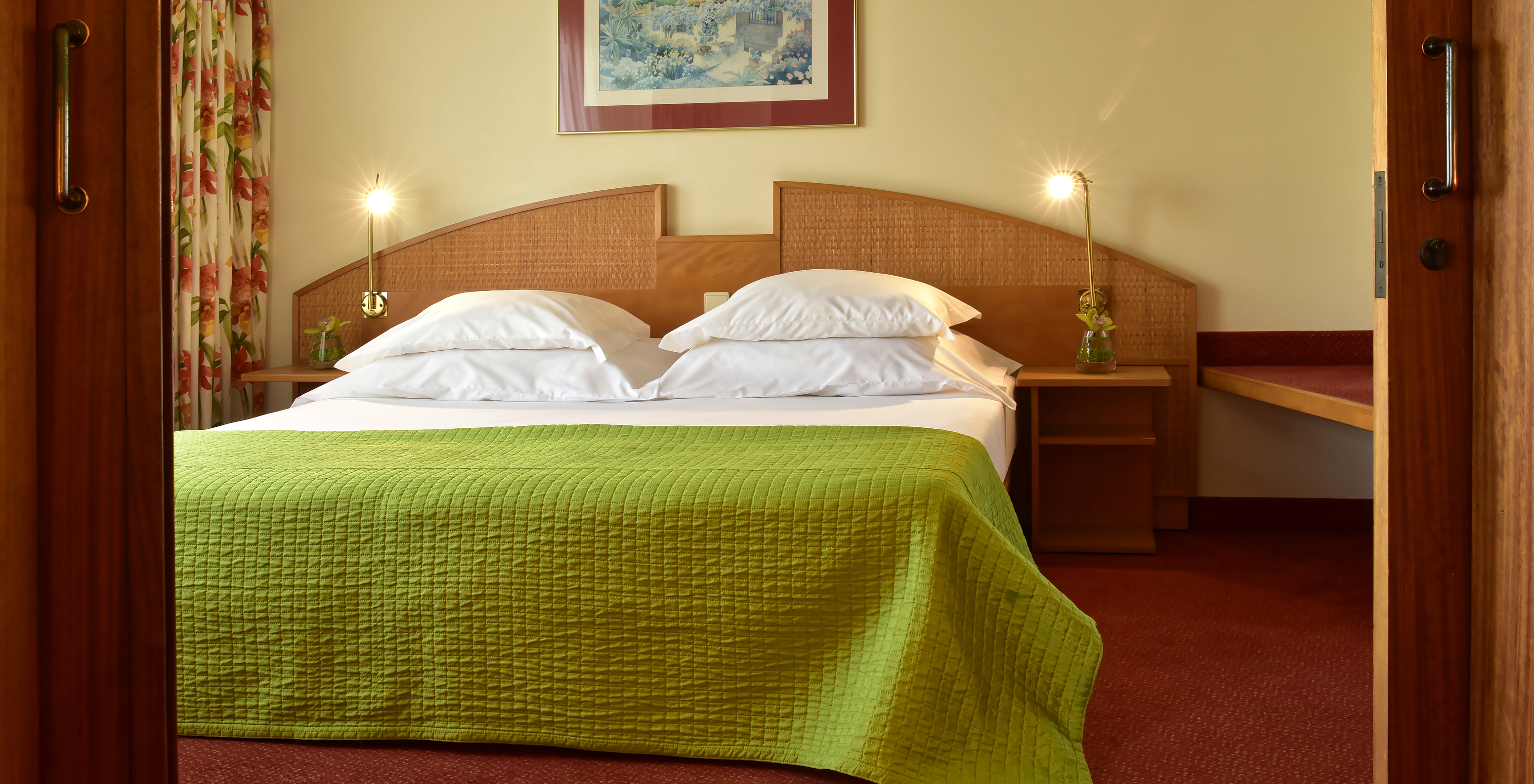 The Junior Suite at Pestana Ocean Bay All Inclusive has a double bed with a green bedspread and a wooden headboard