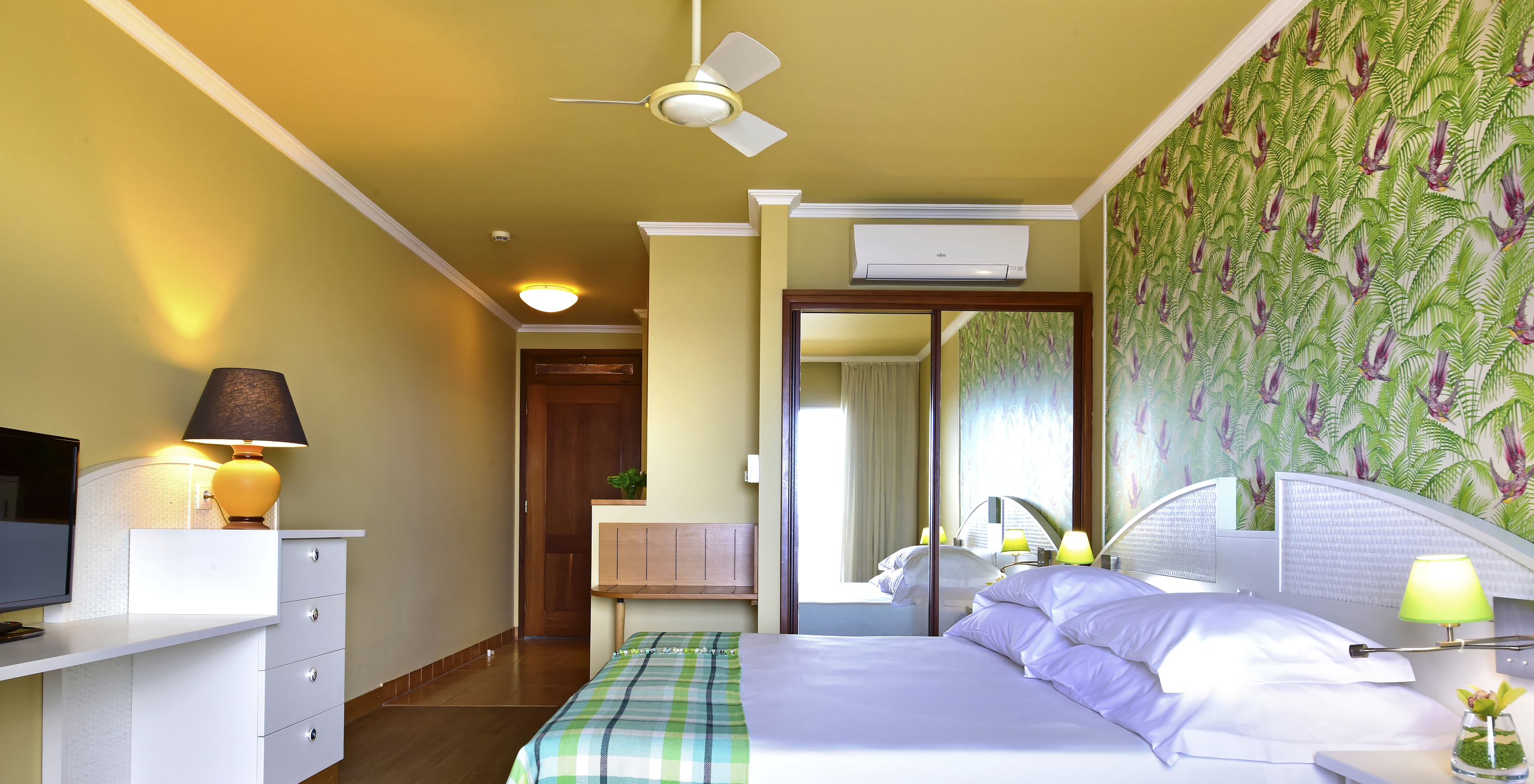 The Premium Studio at Pestana Ocean Bay All Inclusive features a double bed, tropical wallpaper, and a television