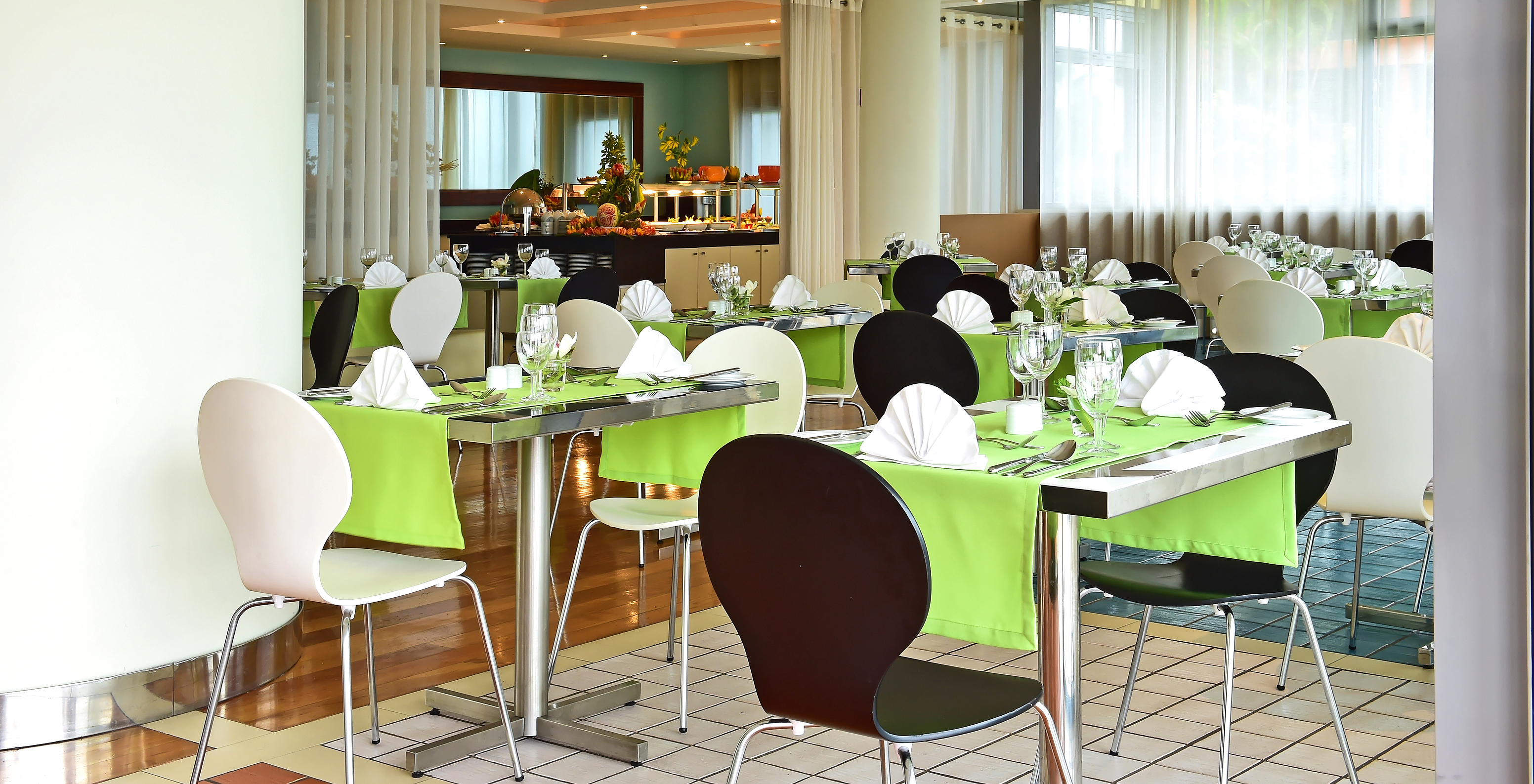 The Breezes restaurant at the 4-Star Hotel by the Sea in Funchal features several tables with green tablecloths and a buffet