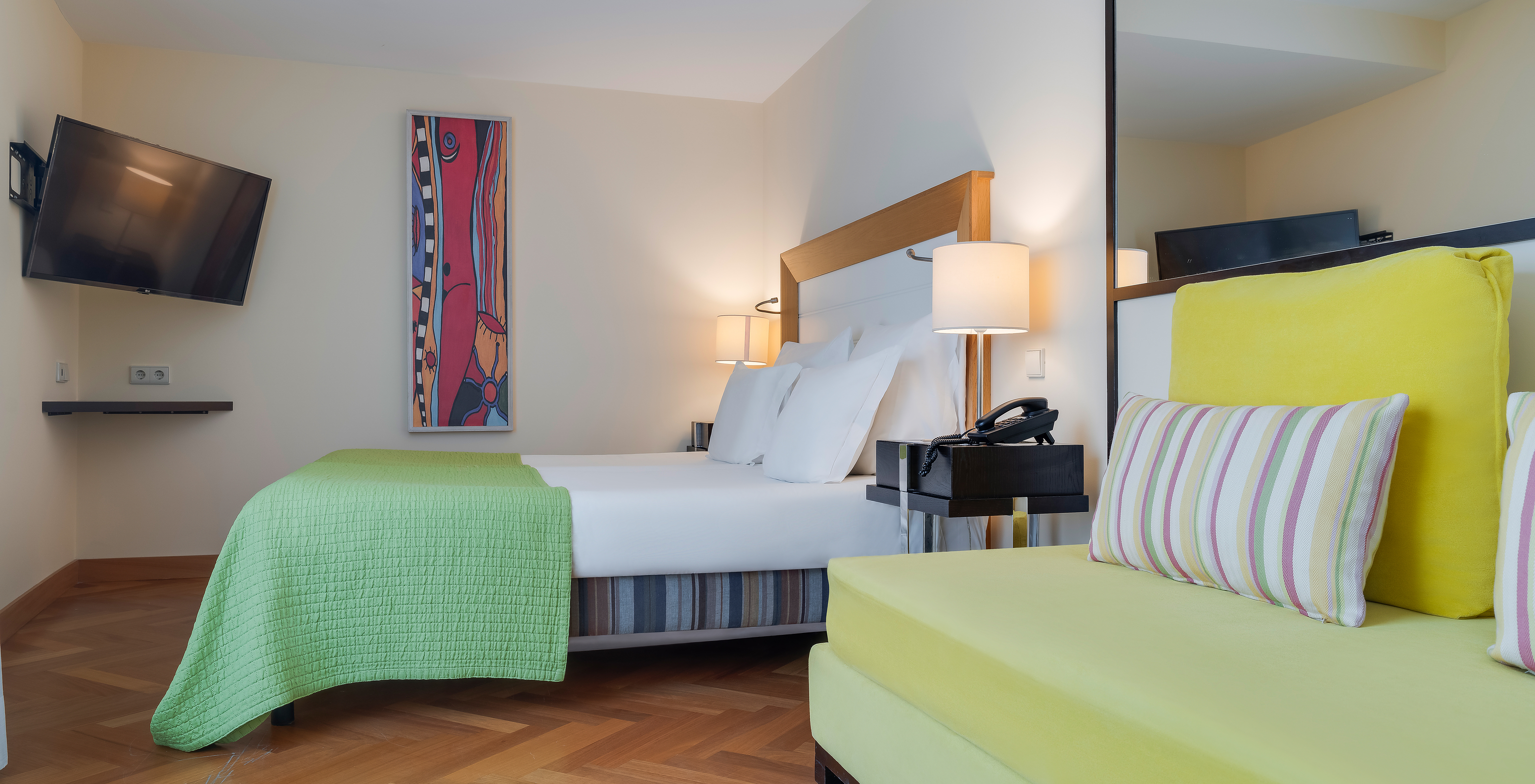 The Classic Twin of Pestana Promenade has a double bed with a green bedspread and a mounted television