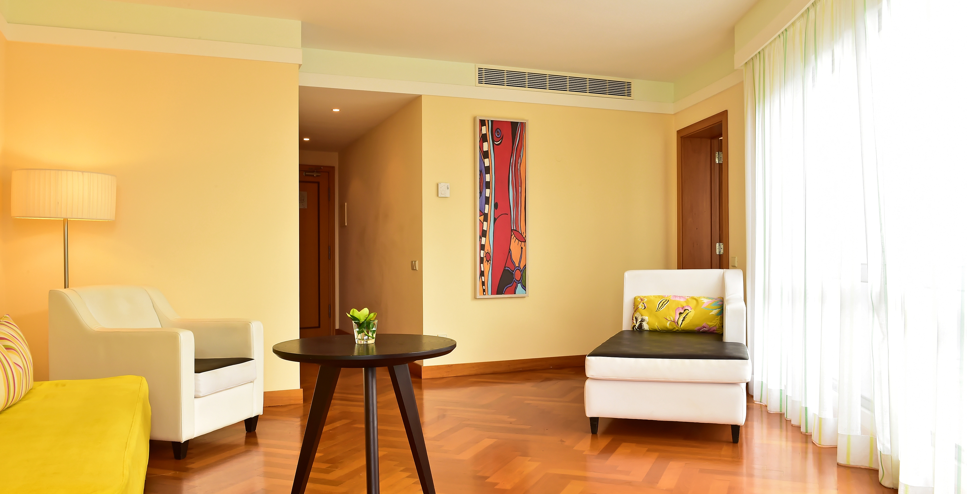 The Suite Sea View of Pestana Promenade has a living room with a large window, a green sofa, and two armchairs