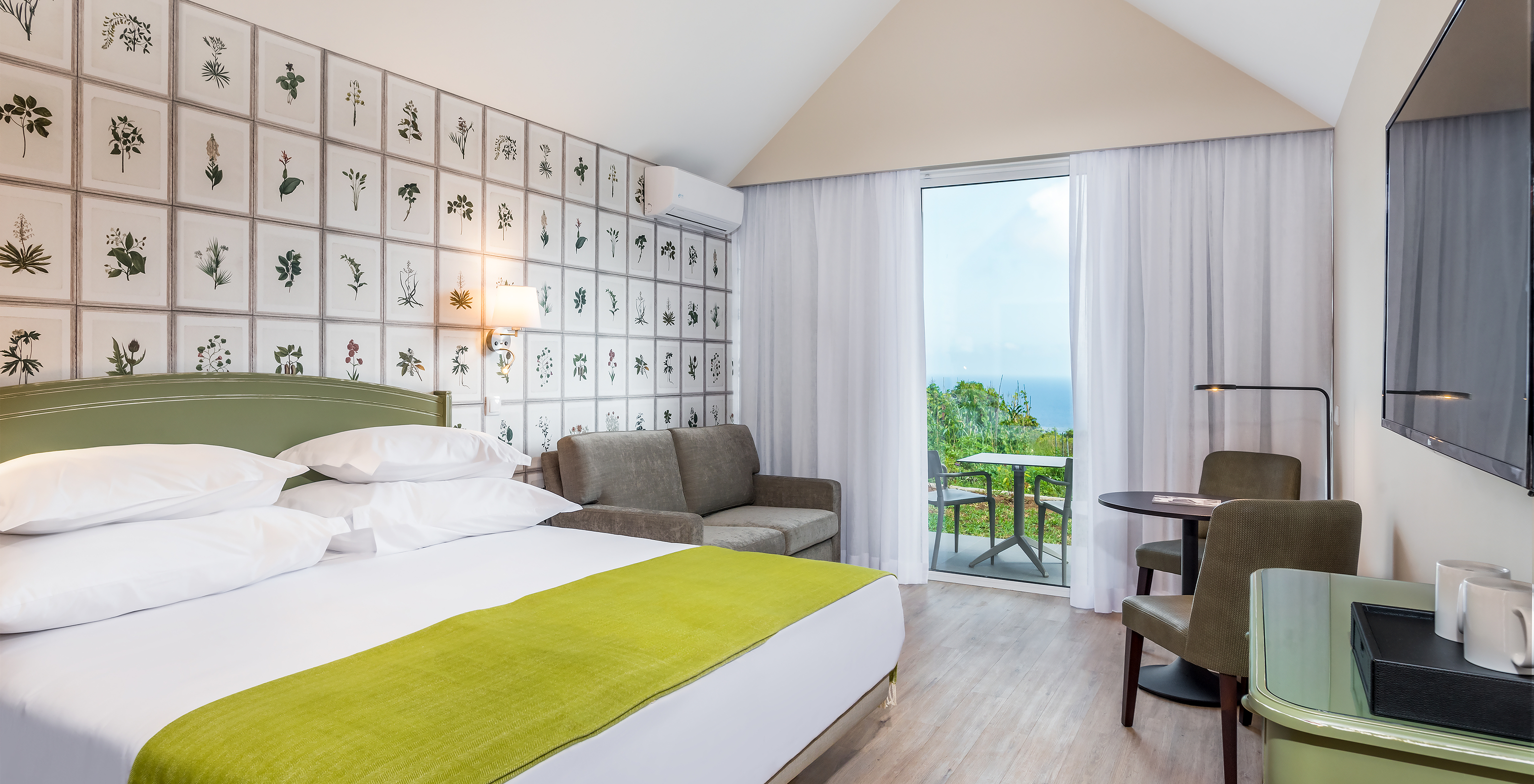 The Garden View Studio of Pestana Quinta do Arco has a double bed, sofa, side table, television, and balcony with sea view