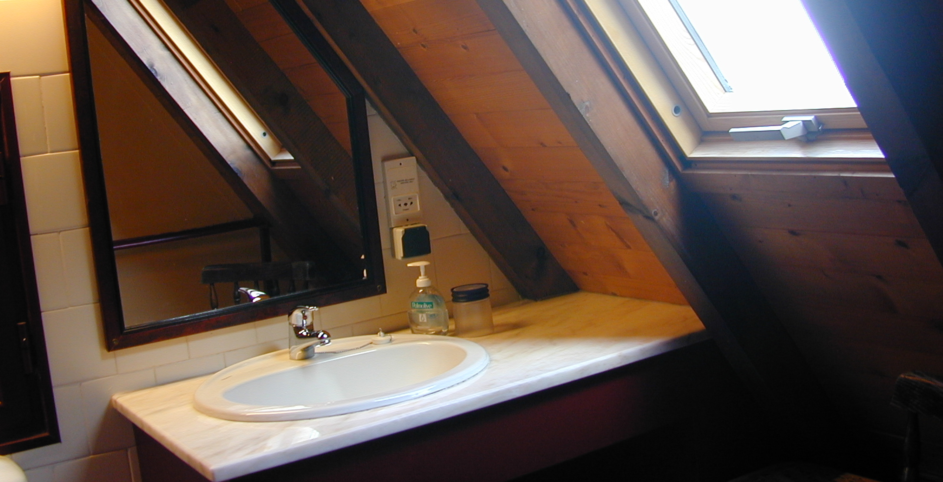 The Duplex Villas of Pestana Quinta do Arco have a bathroom with sink and sloped window, with mirror and wooden ceiling