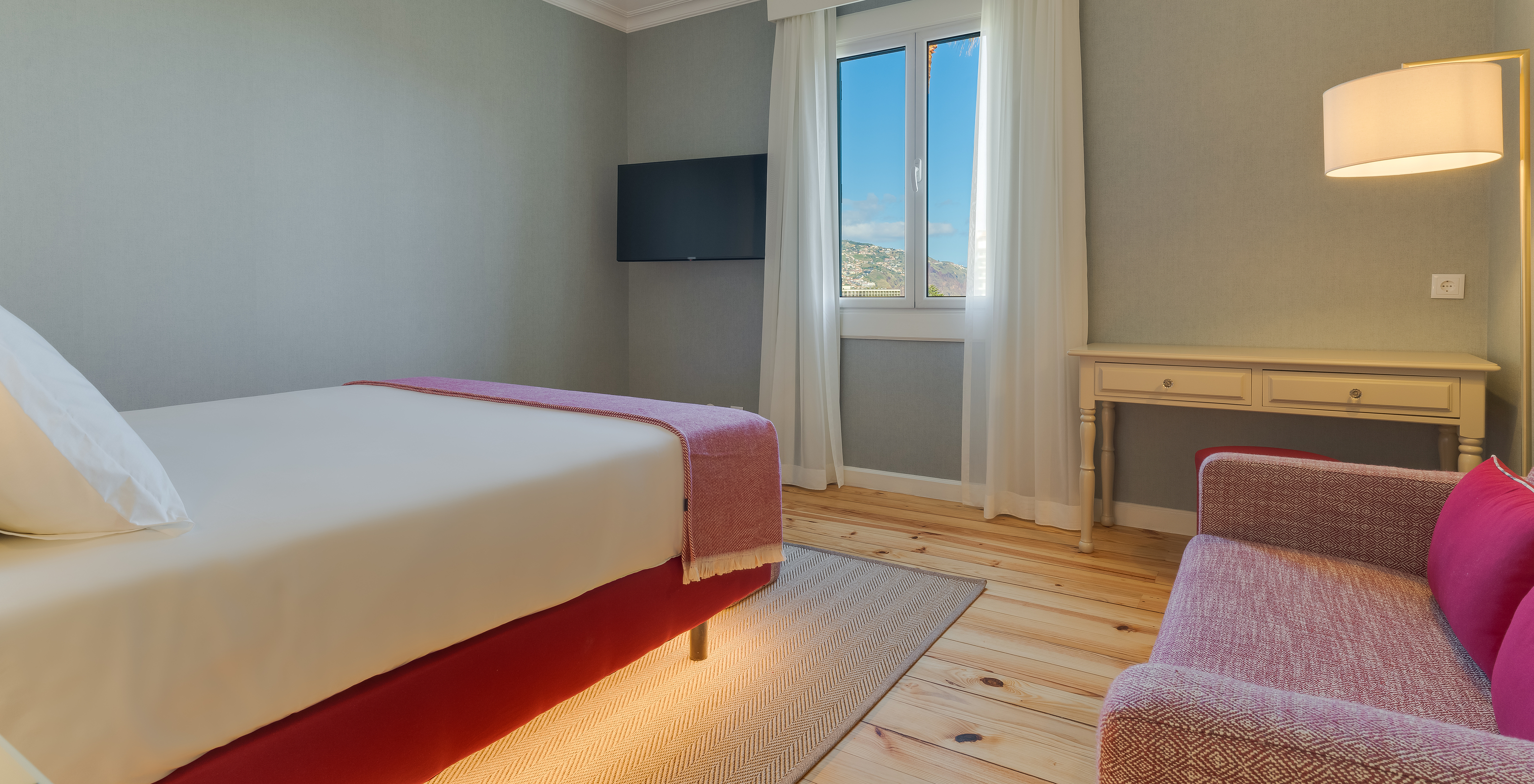 Partial Sea View room at Pestana Quinta Perestrello has a TV in front of the bed, a sofa, and a cabinet