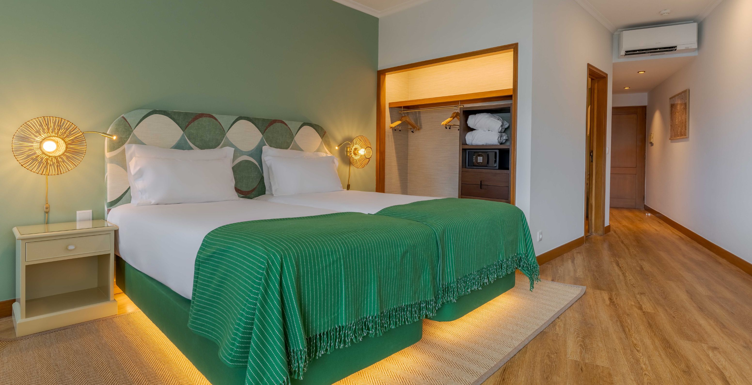 The Superior Lateral Sea View room at Pestana Vila Lido Madeira features a double bed with a green headboard and wardrobe