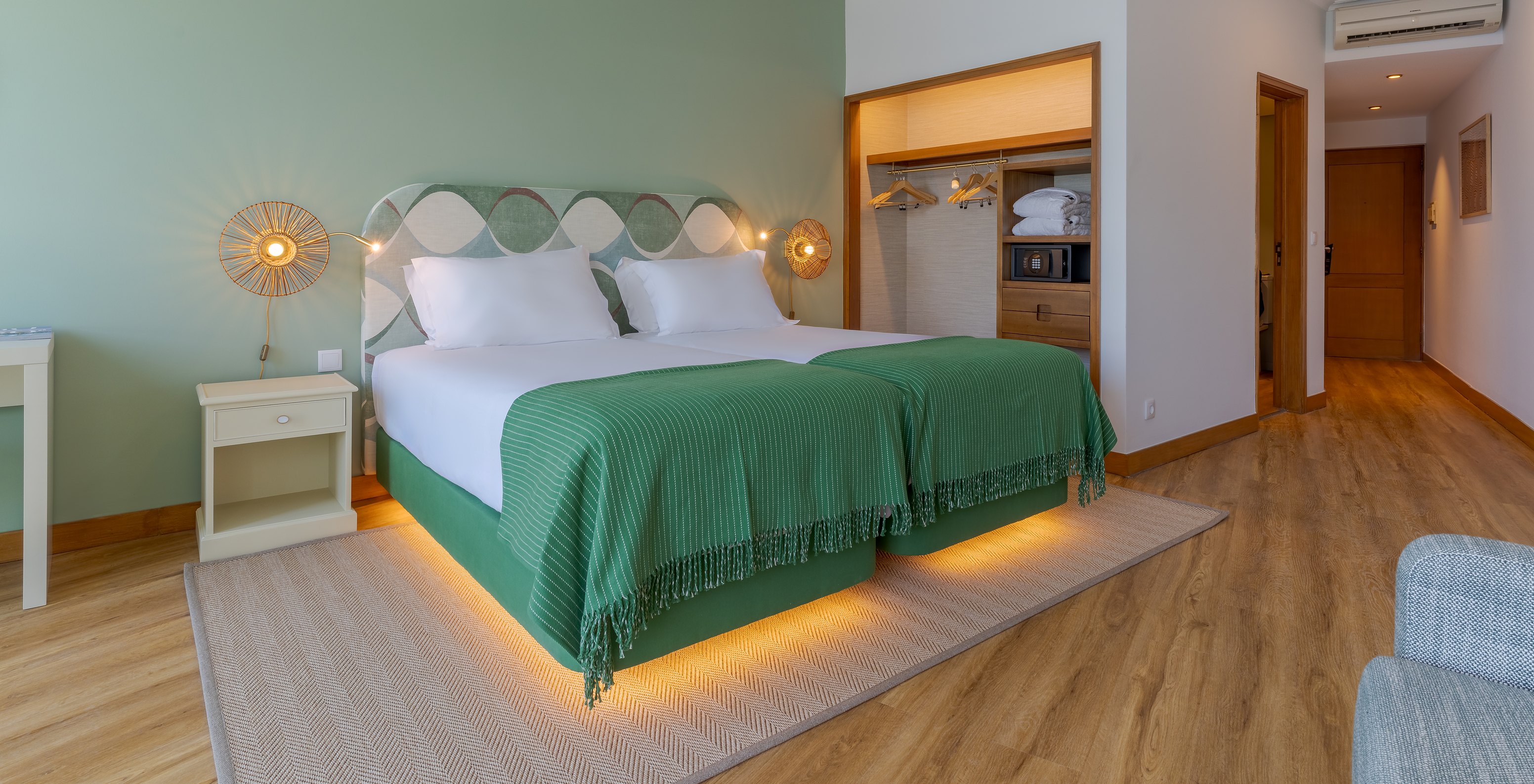 The Superior Sea View room at Pestana Vila Lido Madeira features green tones, two beds, and a wardrobe with safe