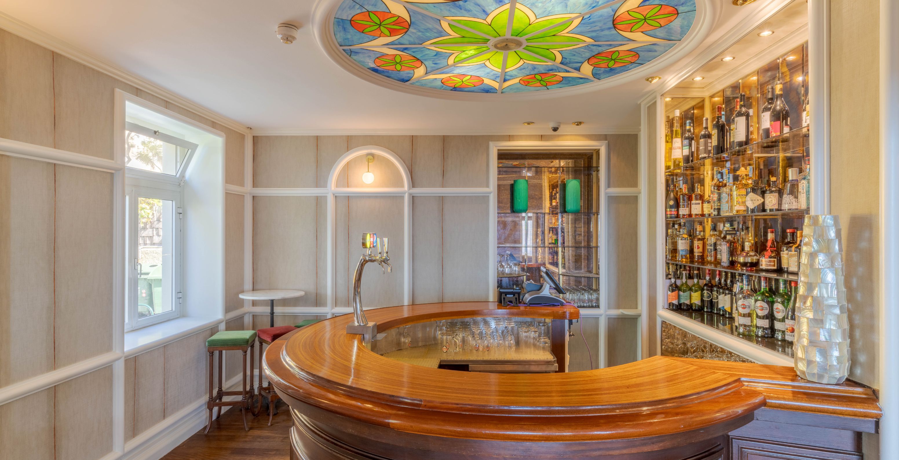 The Vila Lido Bar, at the Seaside Hotel in Funchal, has a semi-circular wooden bar with a colorful stained-glass ceiling.