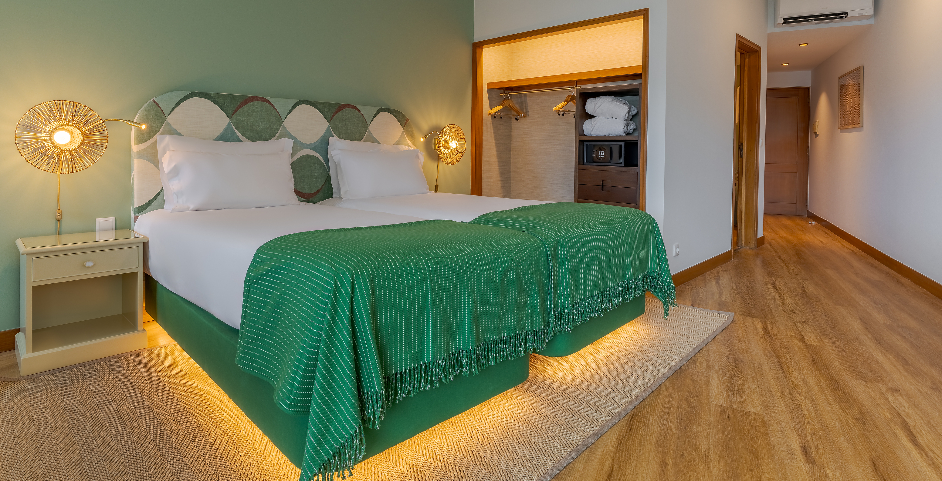 The Classic Lateral Sea View room at Pestana Vila Lido Madeira features green tones, a double bed, and a wardrobe with safe