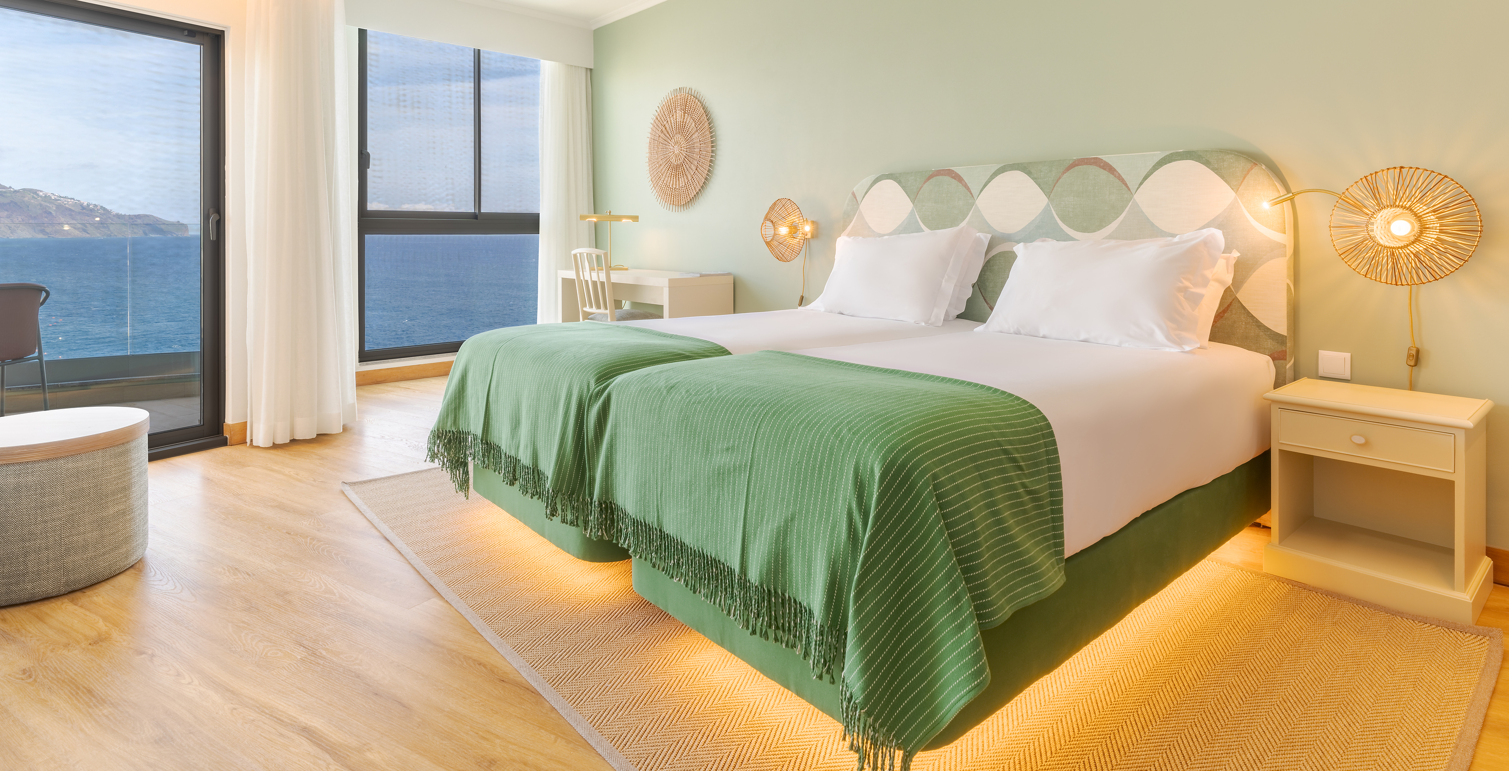 The Superior Sea View room at Pestana Vila Lido Madeira features green tones, two beds, a desk with chair, and a balcony