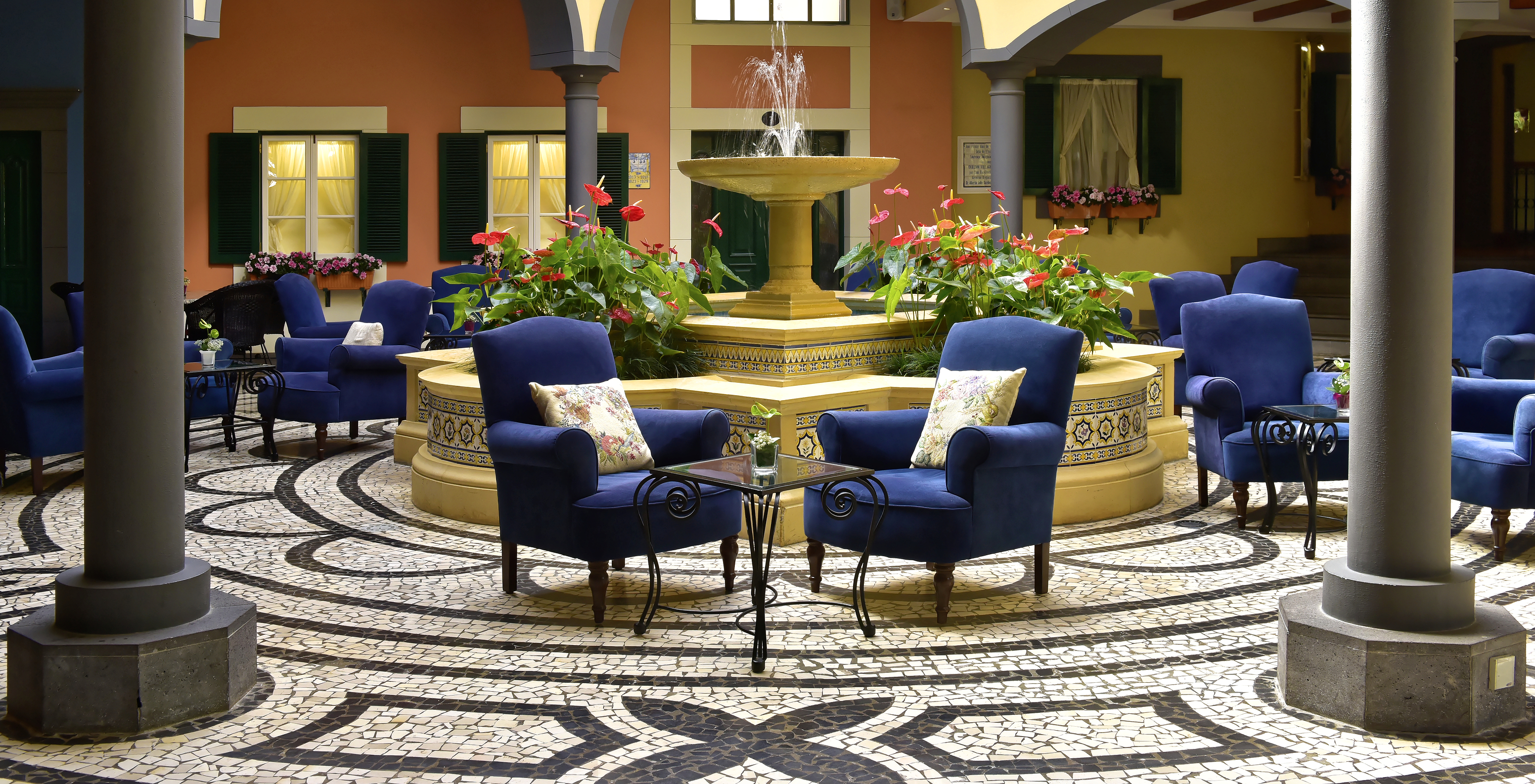 Lounge in the courtyard of Pestana Village, a Hotel with Pool in Funchal, with blue sofas and a fountain