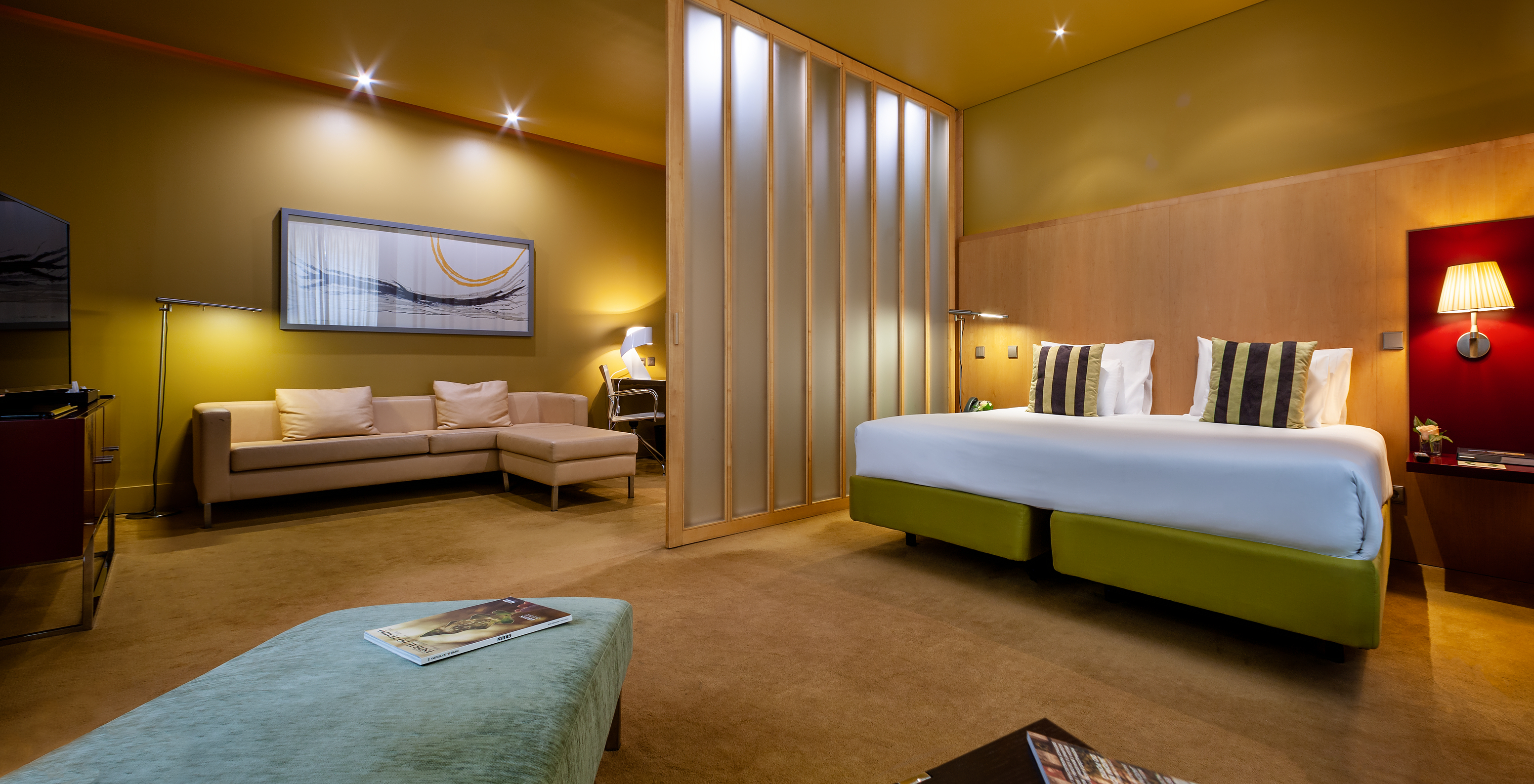 The Standard Suite of Pestana Palácio do Freixo has a double bed and a separation for a room with a sofa and a painting