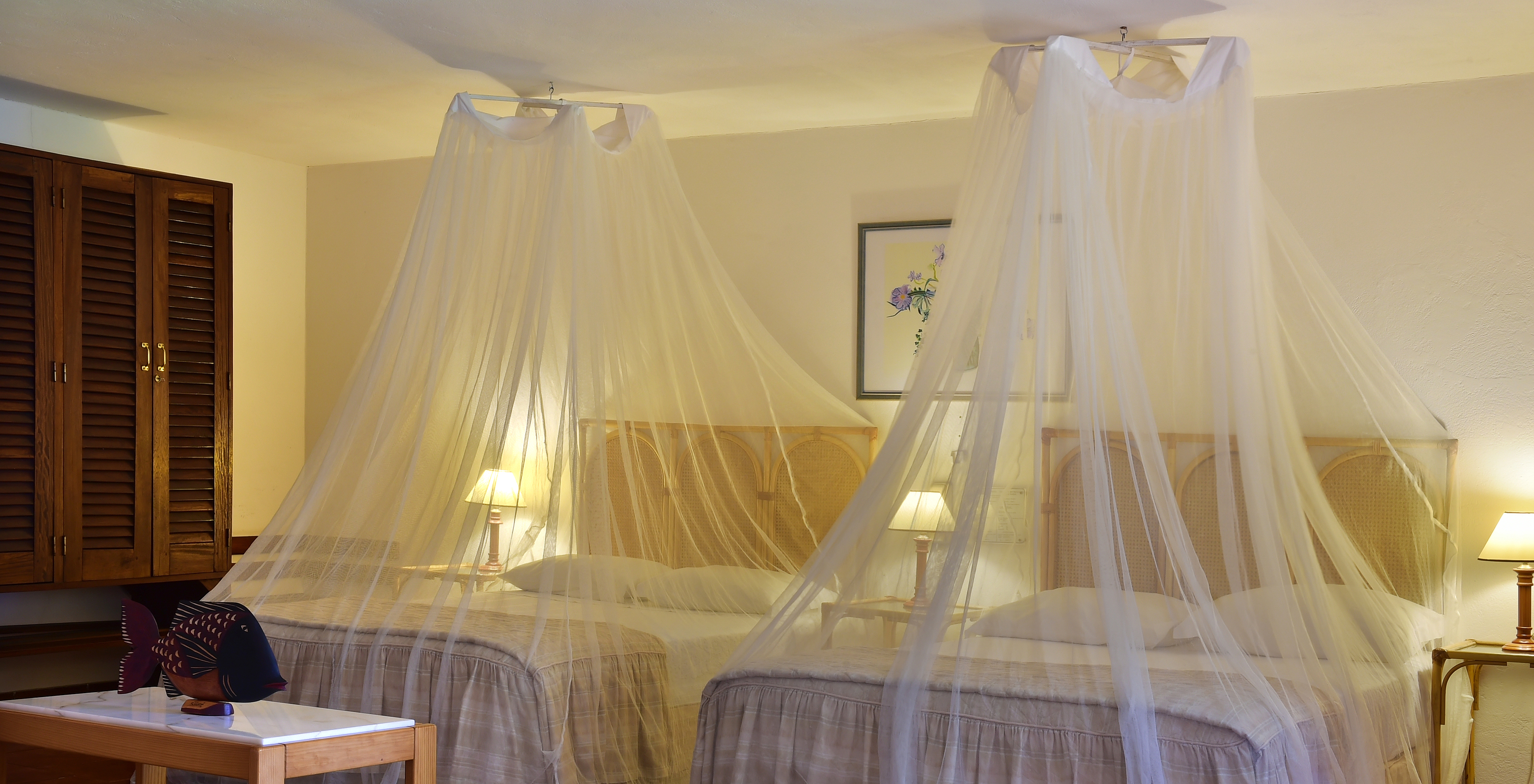 The Classic room at Pestana Miramar São Tomé has two double beds with mosquito nets and three bedside tables