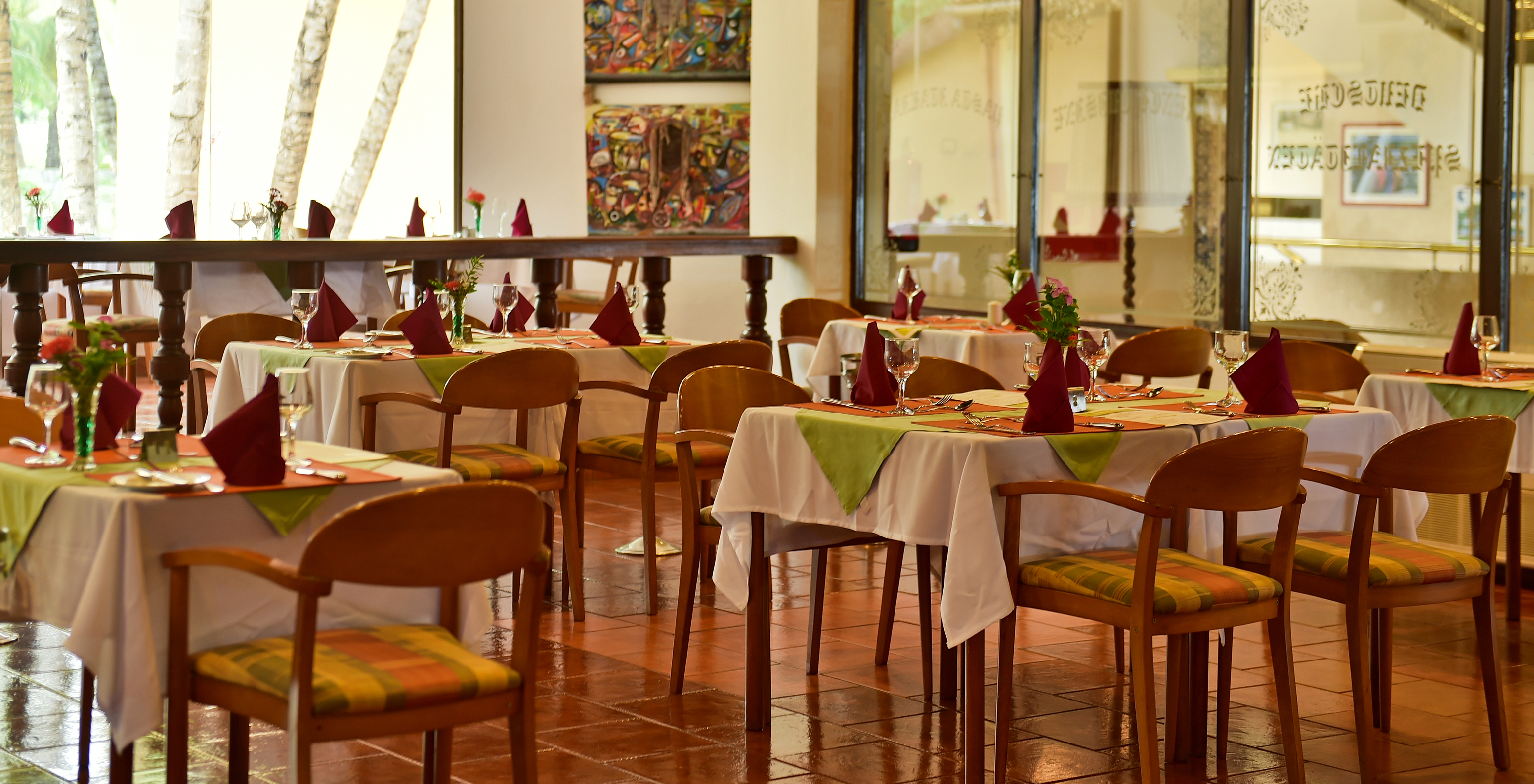 Restaurant of hotel with pool, beachfront, with set tables featuring cutlery, glasses and napkins