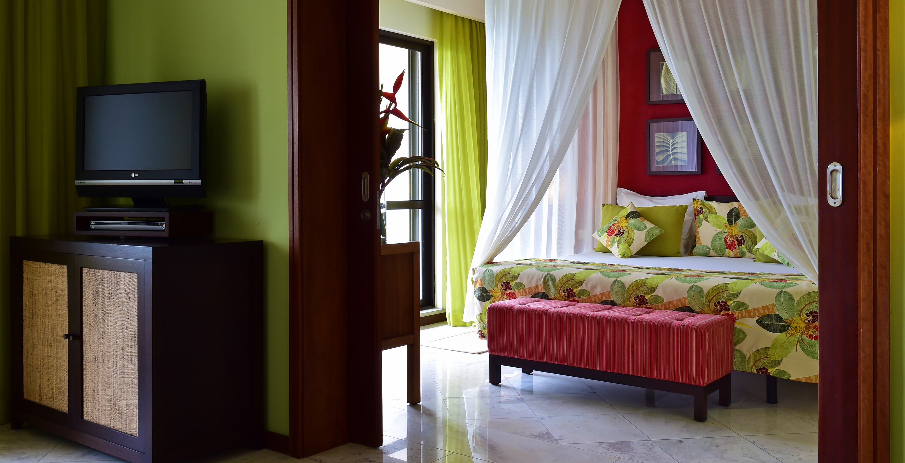 The Central Suite of Pestana São Tomé has a king-size double bed with a canopy and an ottoman at the foot