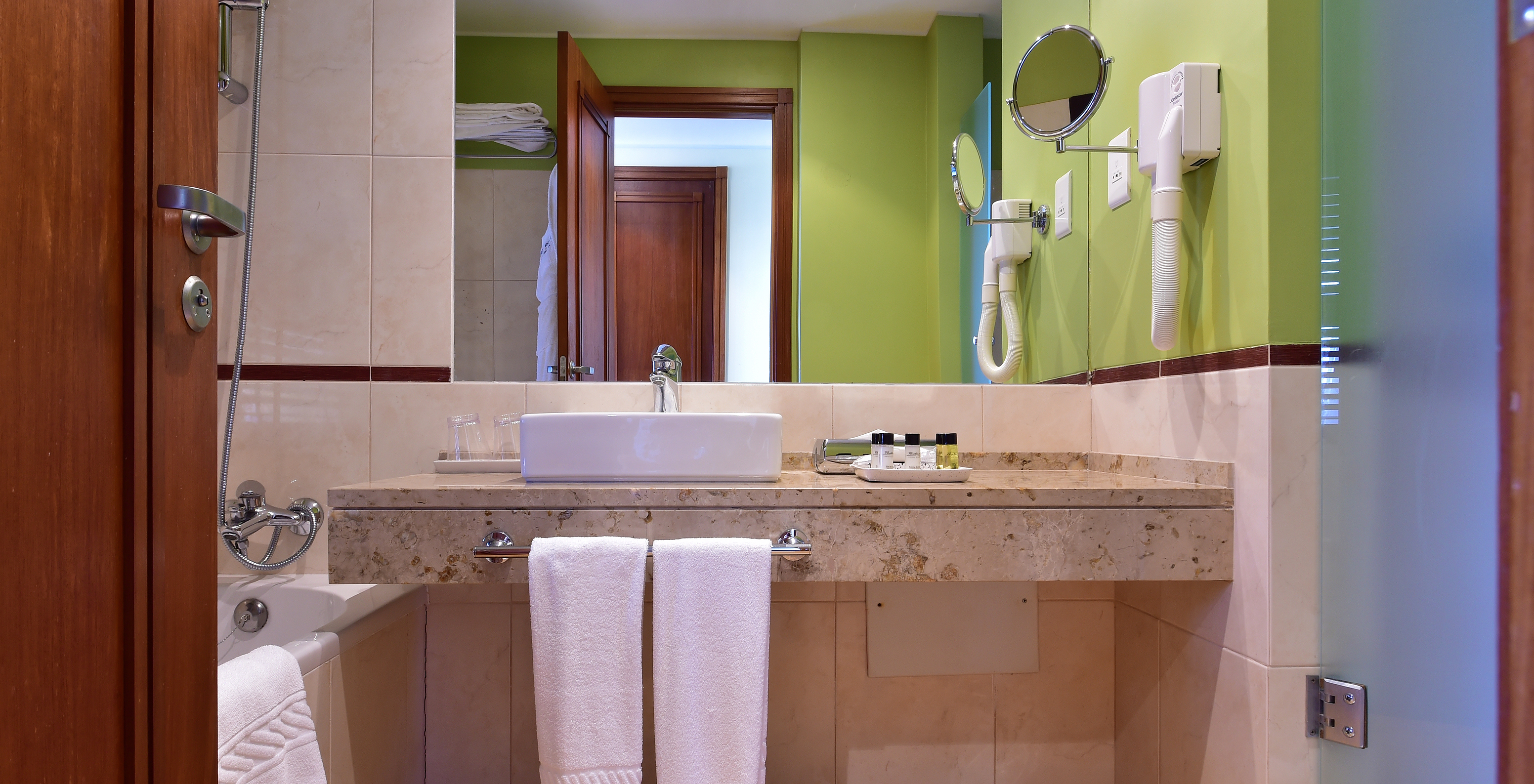 The Sea View Room of Pestana São Tomé has a bathroom with bathtub with shower and a neutral and green decor