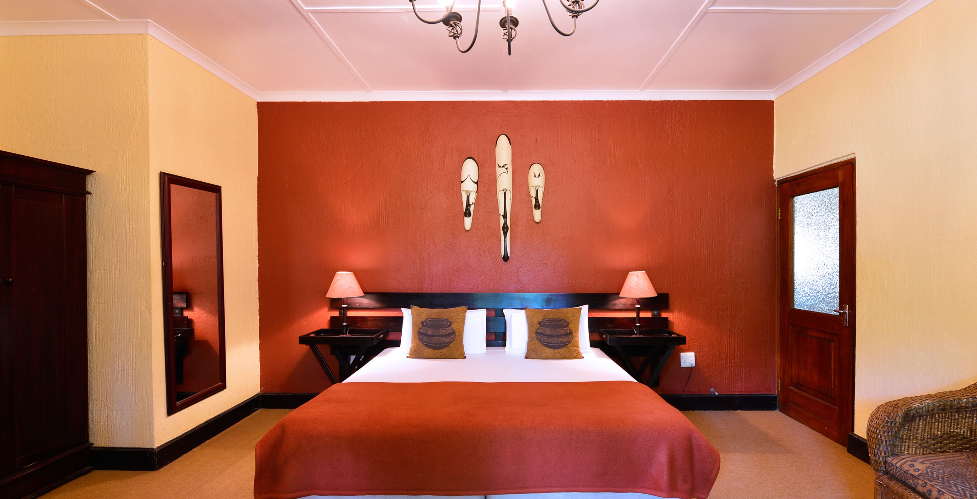 The Rhino Family Cottage at Pestana Kruger Lodge has a double bed and typical African decor in red tones