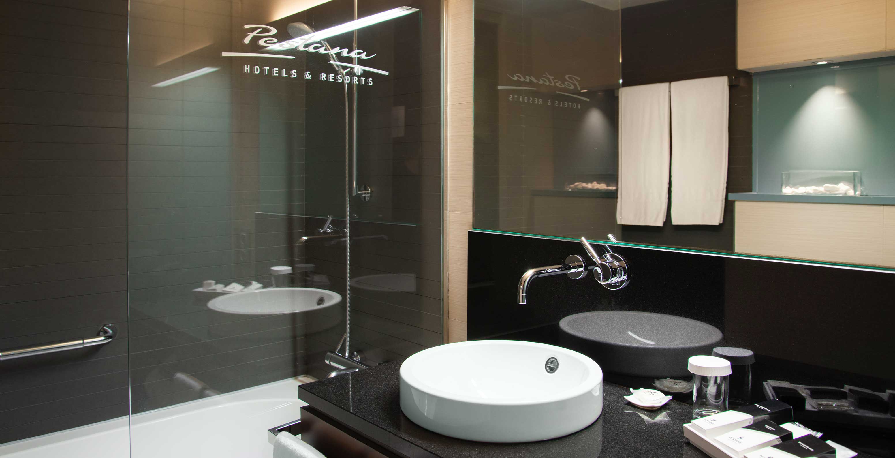 Deluxe King room at Pestana Arena Barcelona has a bathroom with bathtub with shower and a sink with mirror