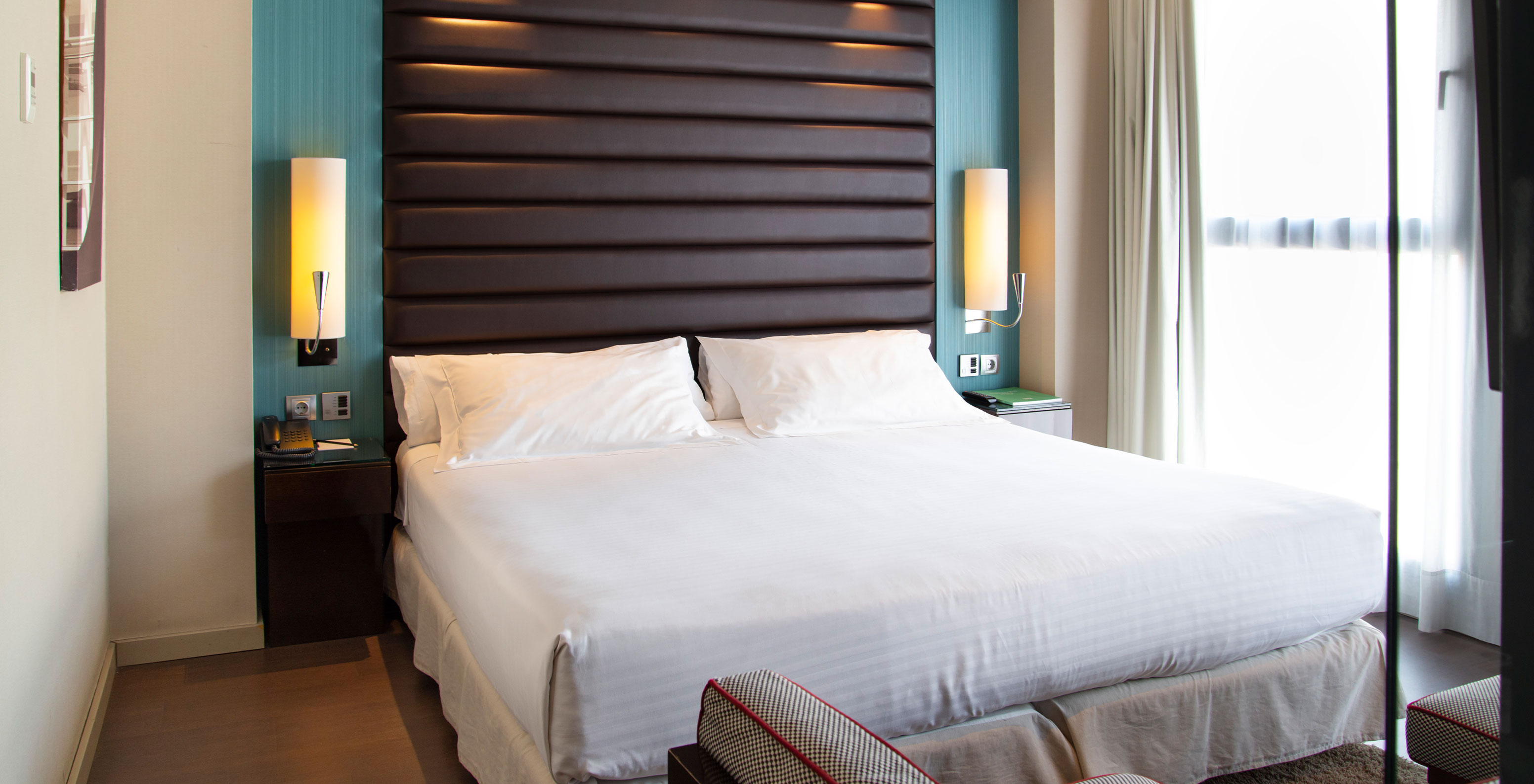 Premium Twin room at Pestana Arena Barcelona has a double bed, two bedside tables, a sofa and a window