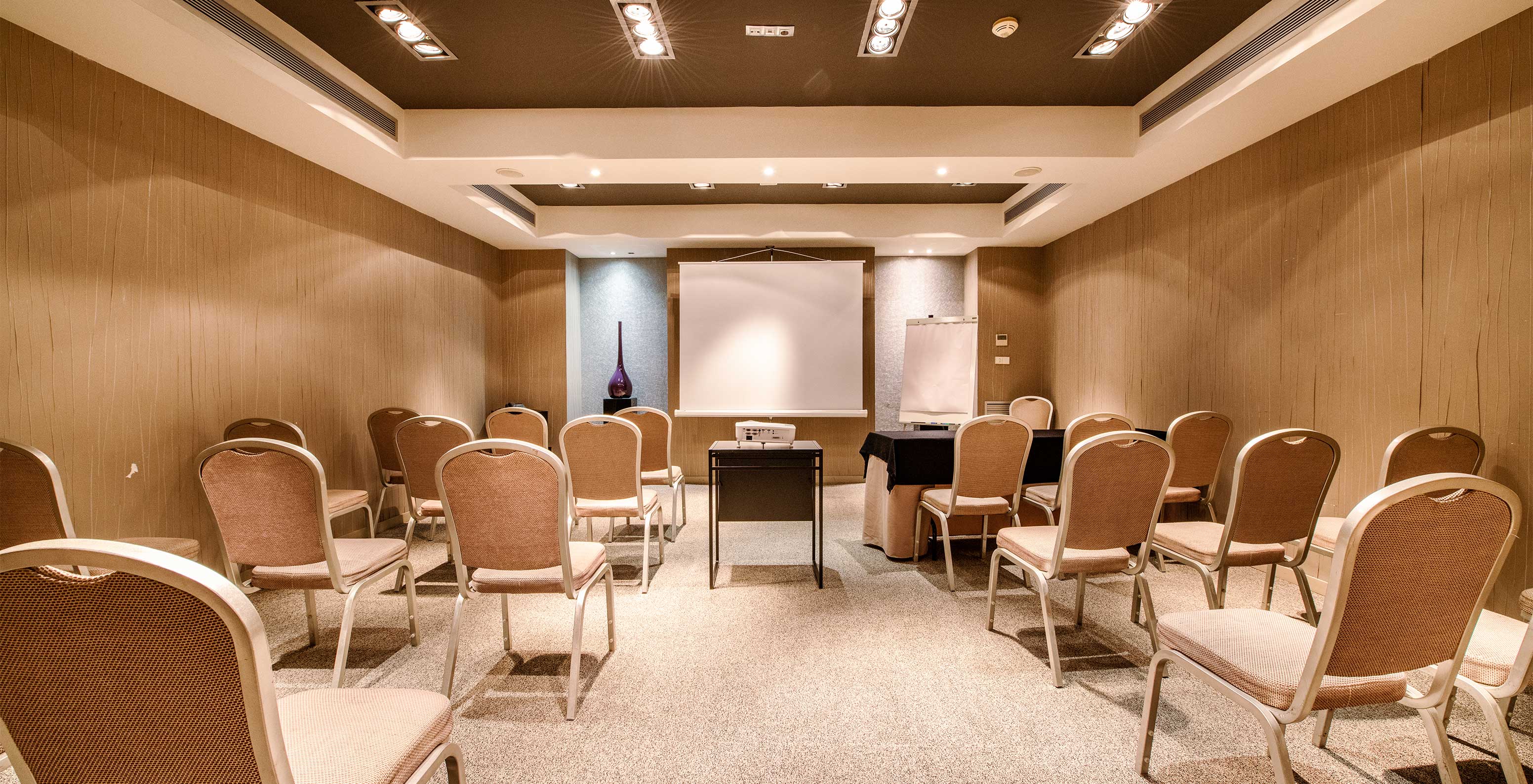 The hotel in Barcelona has a large room for meetings and conferences, with several chairs and a projector