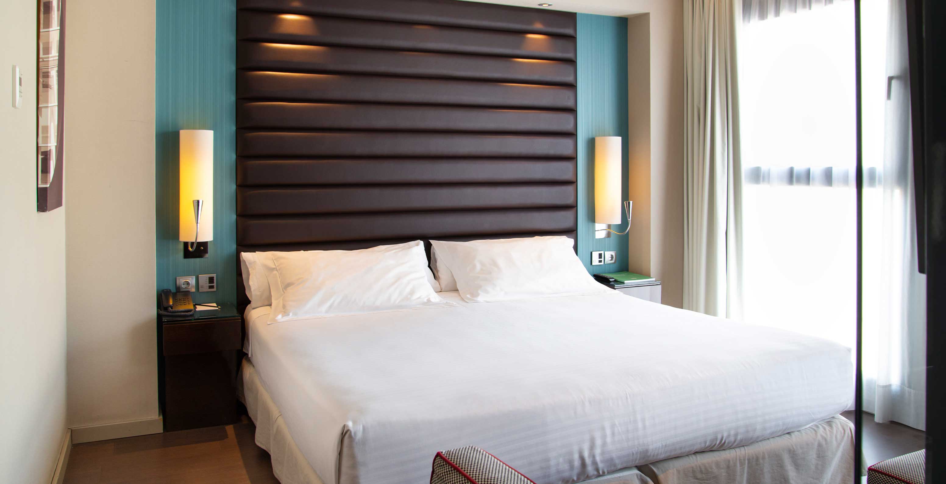 Deluxe King room at Pestana Arena Barcelona has a comfortable double bed with bedside tables and a large window